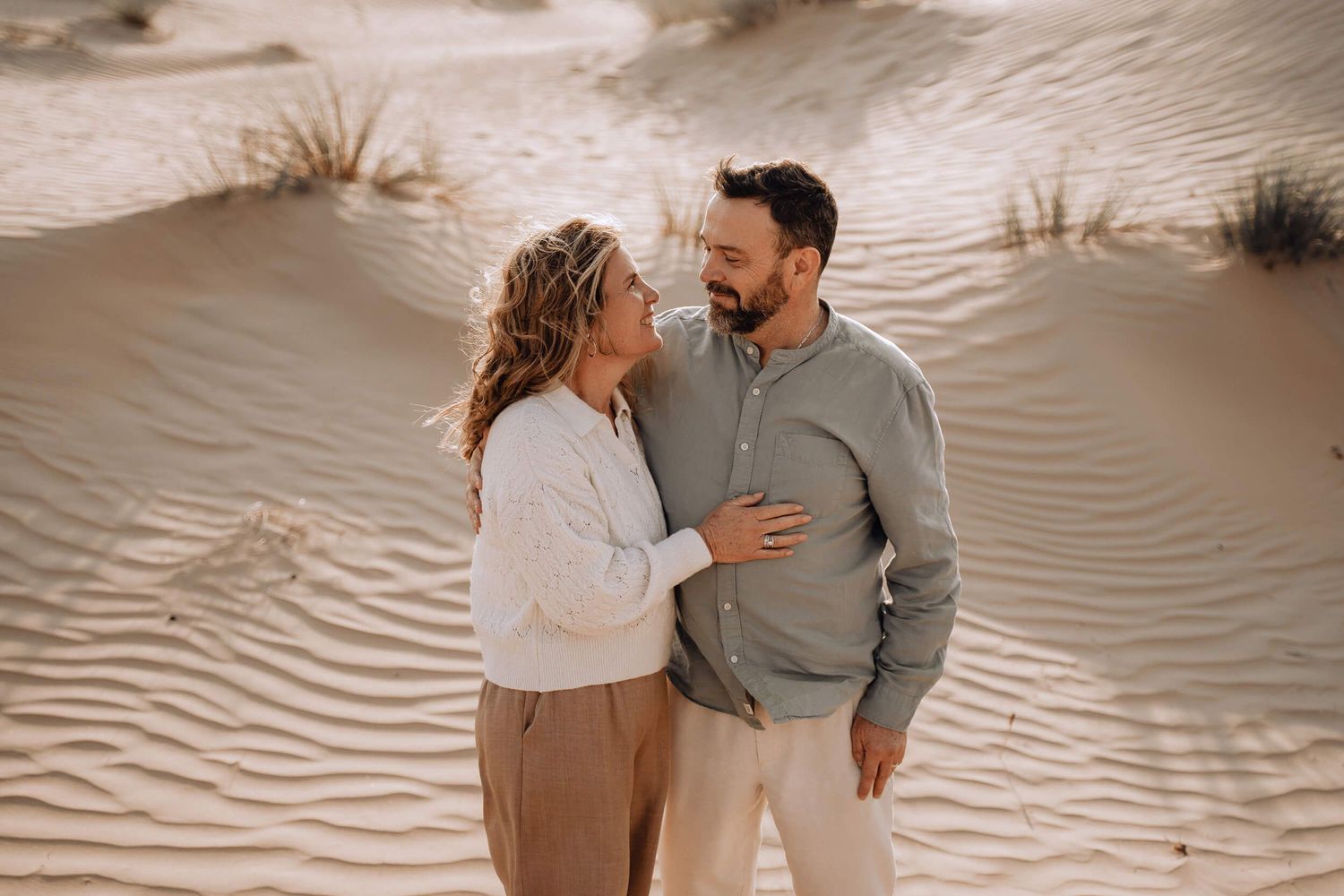 Series of intimate portraits showing affectionate couple against rippling desert sand backdrop.