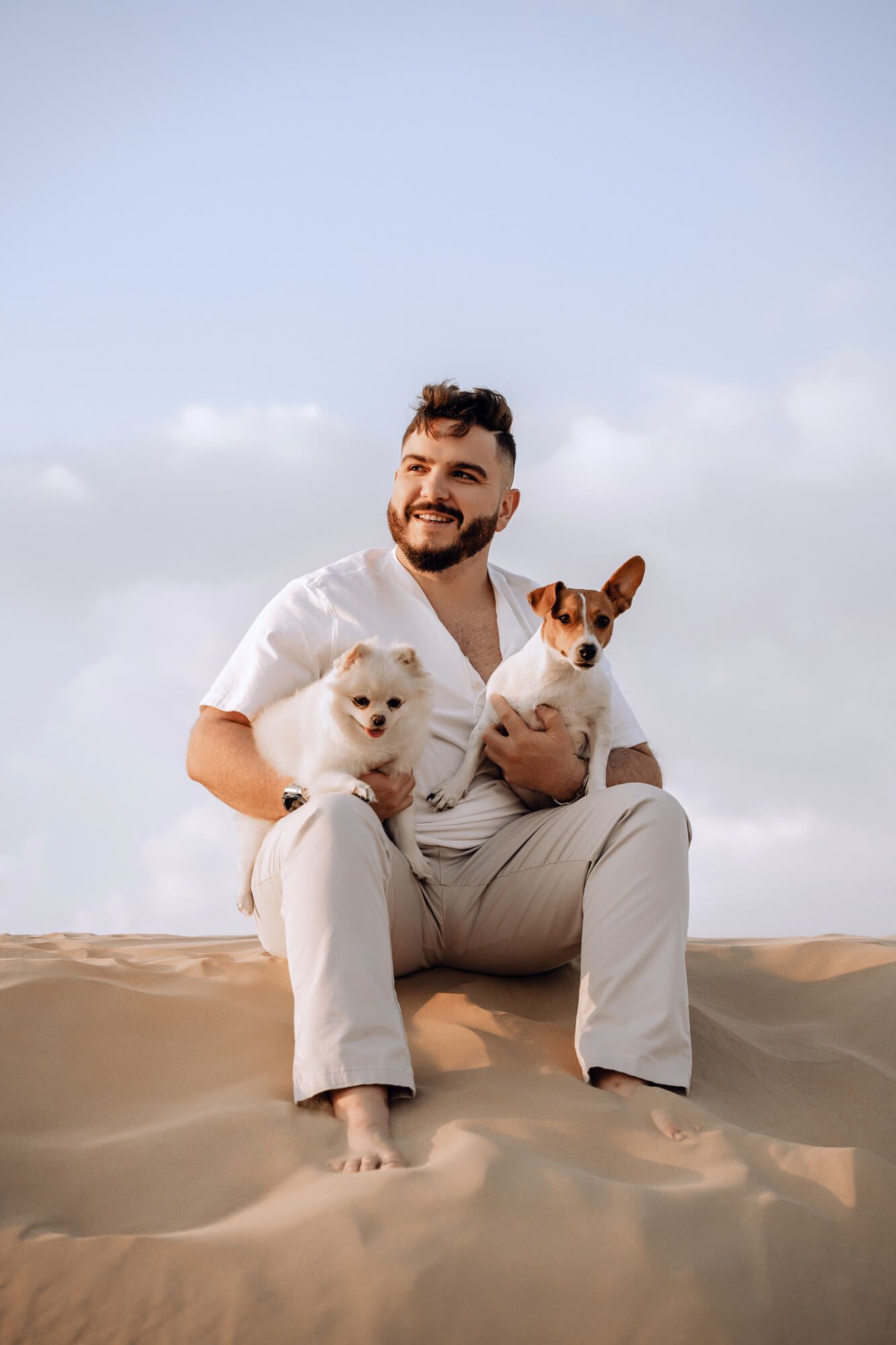 Three small dogs enjoying time together in desert sand dunes landscape.