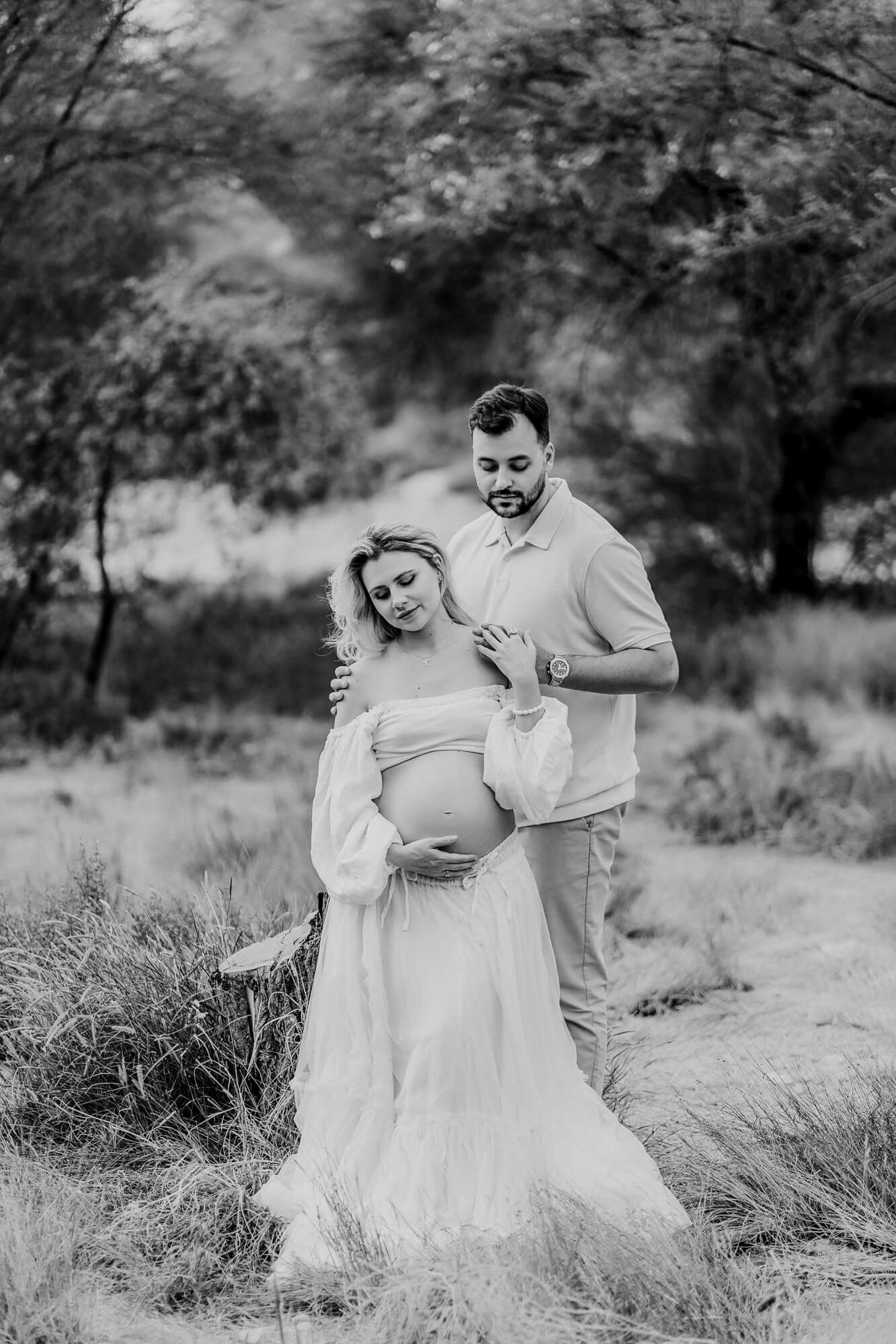 Monochrome maternity photos capturing intimate moments in a natural outdoor setting.