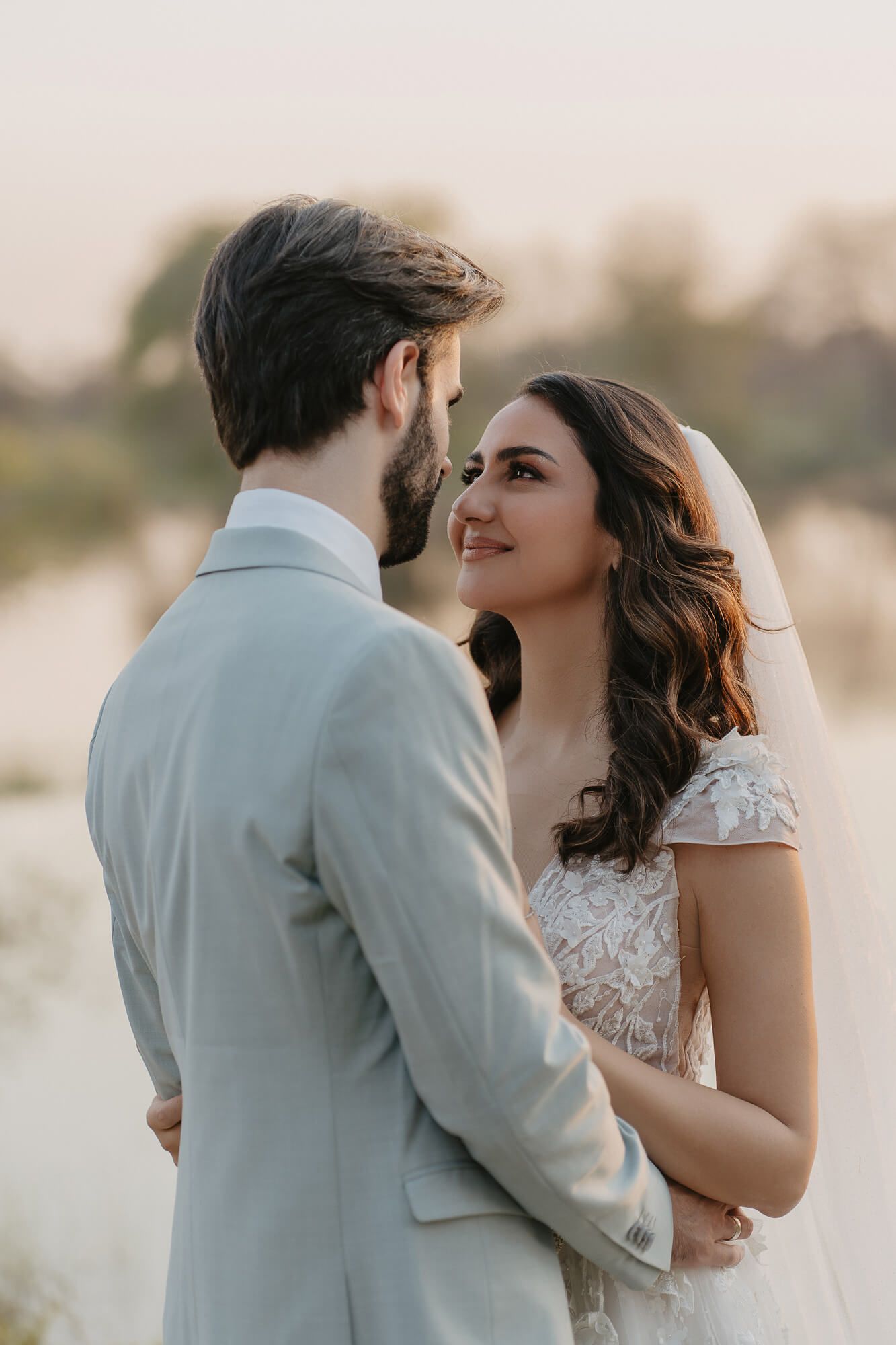 A romantic wedding couple shares intimate moments in a series of soft sunset portraits by the water.