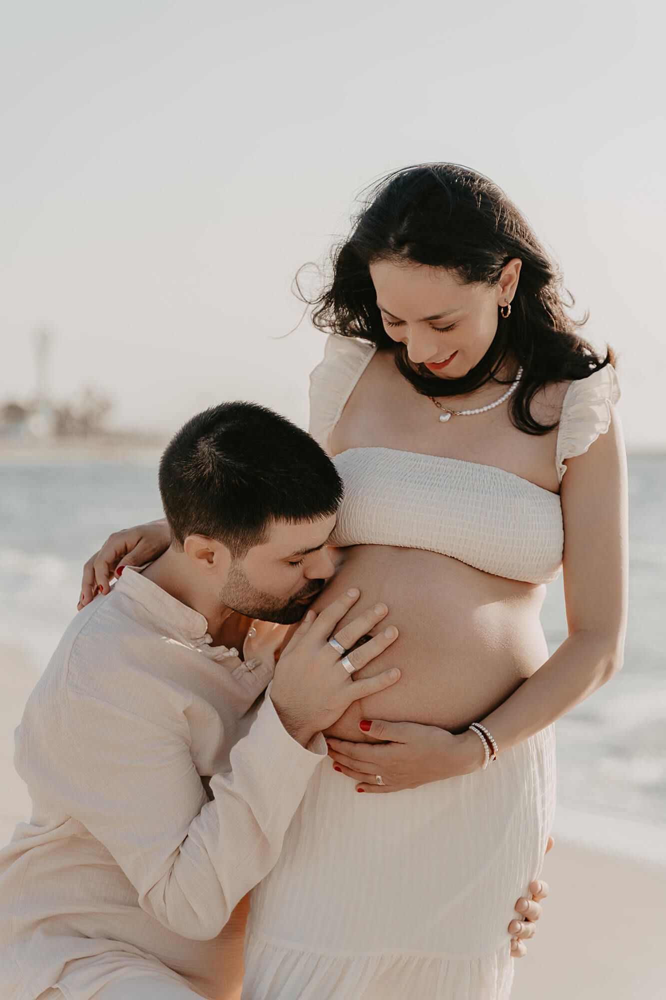 A tender maternity moment at sunset as a couple shares an intimate connection with their unborn baby on the beach.