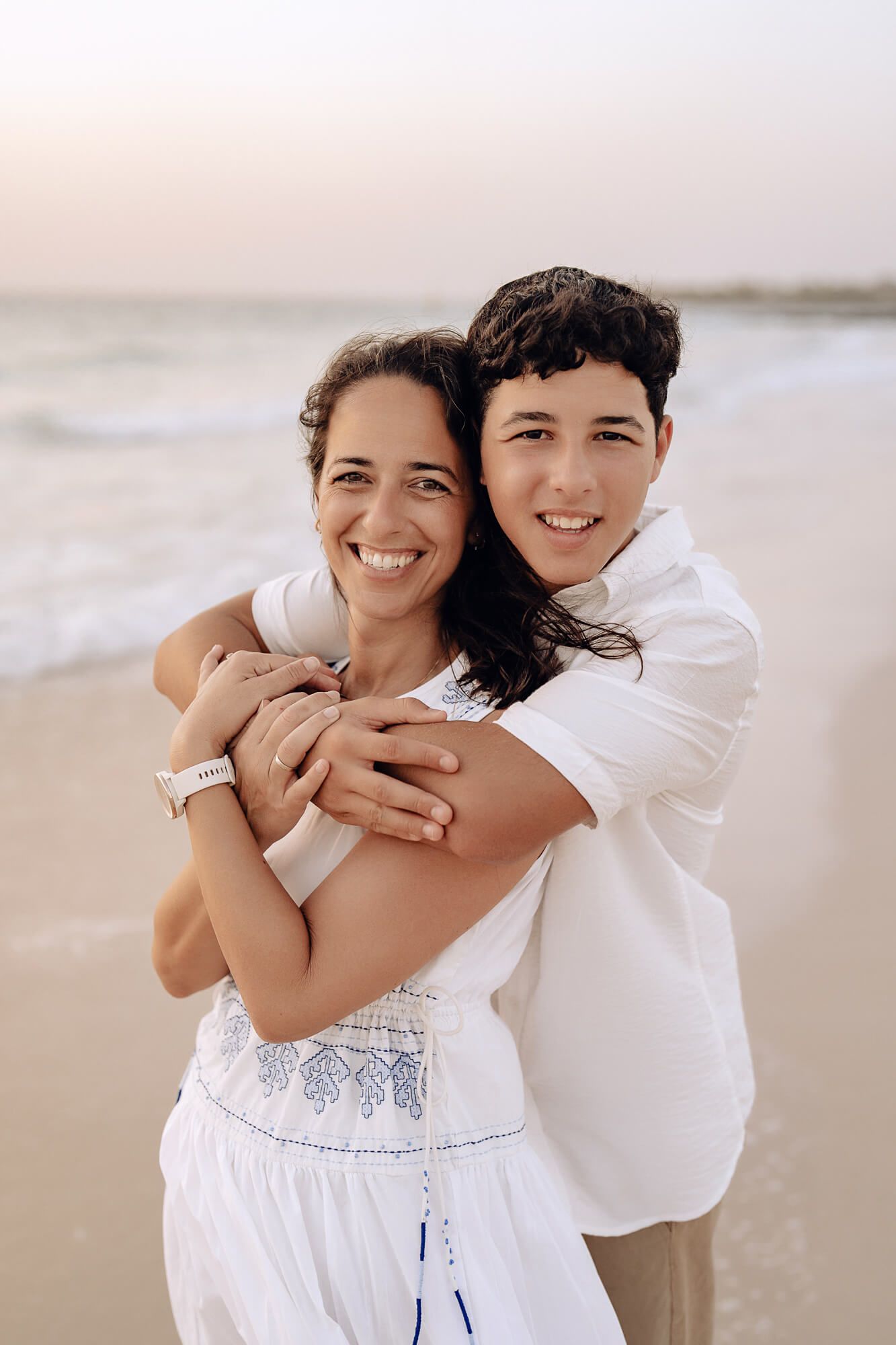A playful beach photo session capturing warm embraces and smiles at sunset.