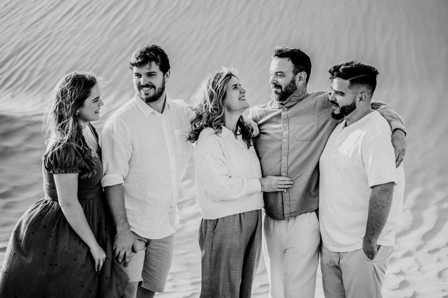 Black and white capture of five people sharing laughs during desert photo session.
