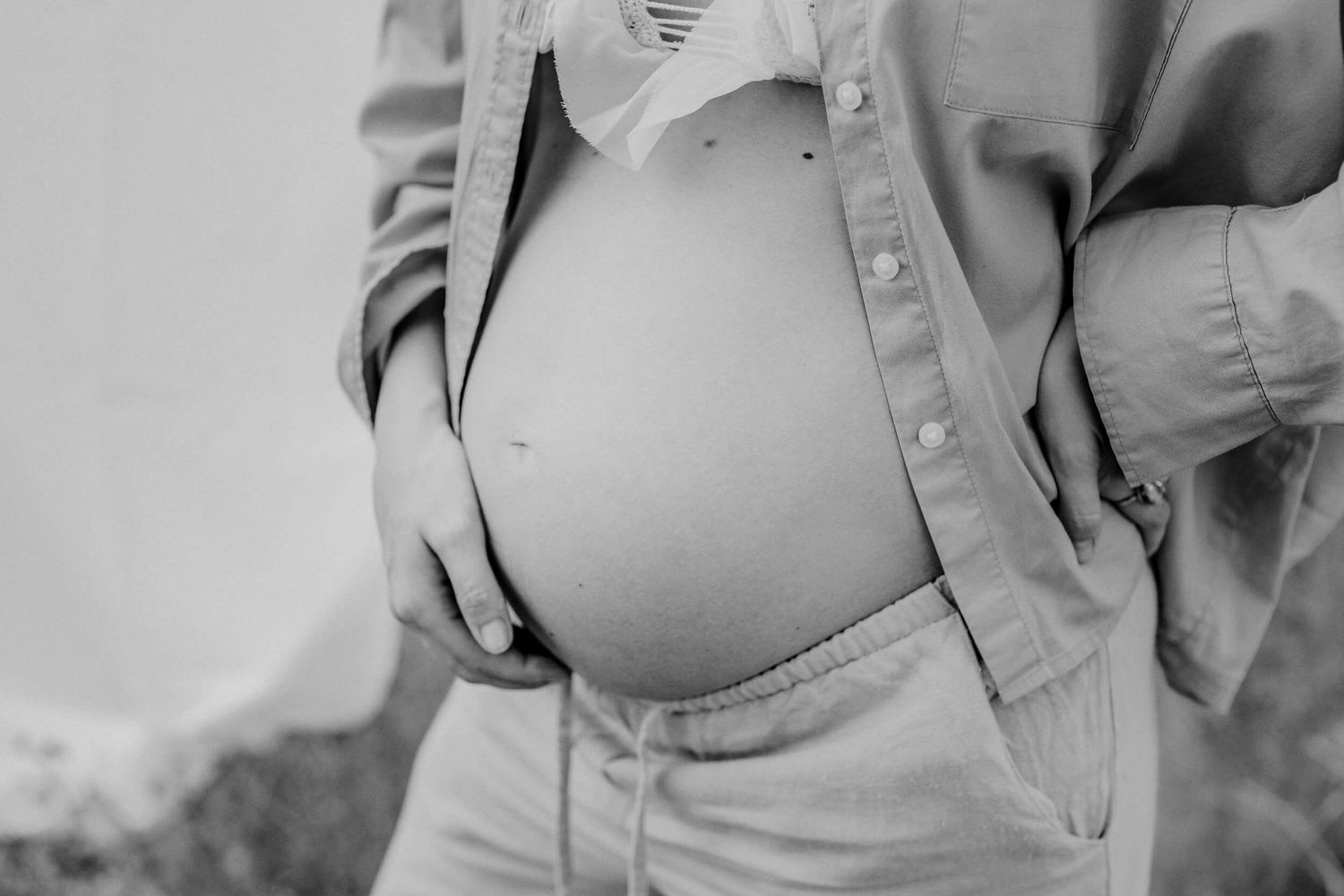 Close-up black and white shot of a pregnant belly with hands gently cradling it.
