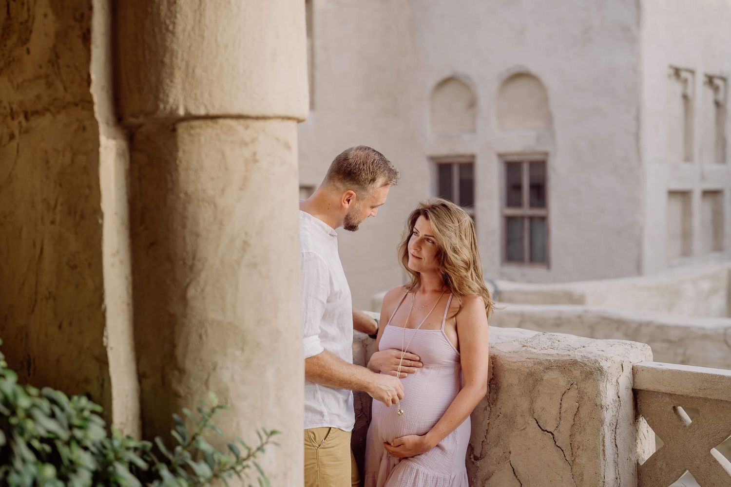 Romantic maternity photography session under elegant stone archways capturing sweet moments at sunset.