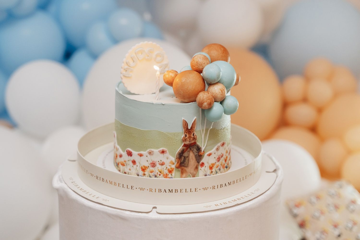 Detailed view of a birthday cake with soft blue and peach decorative elements.
