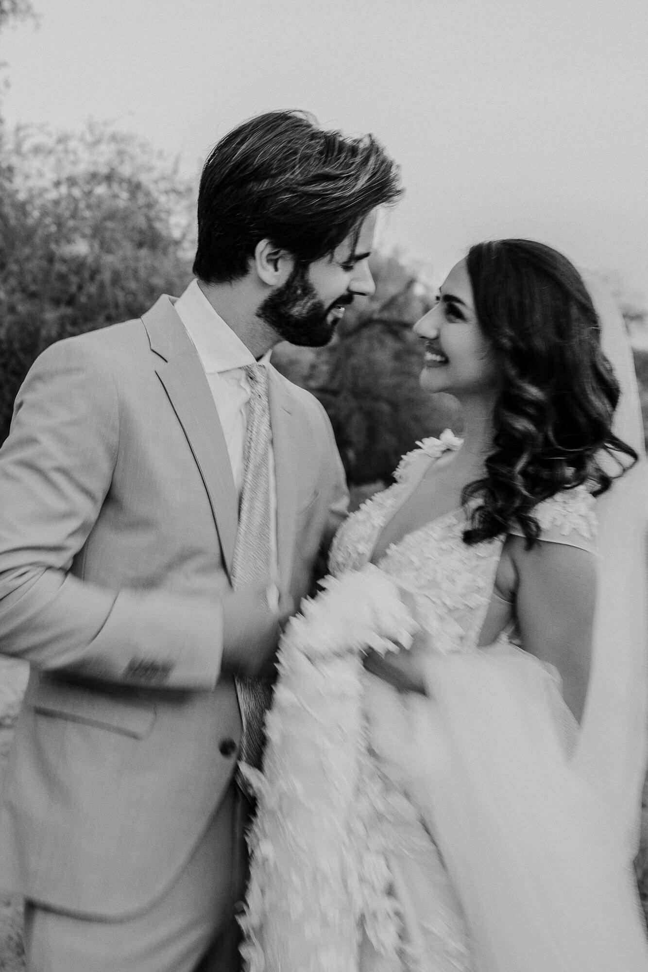 A romantic black and white portrait of newlyweds sharing an intimate moment in their wedding attire.