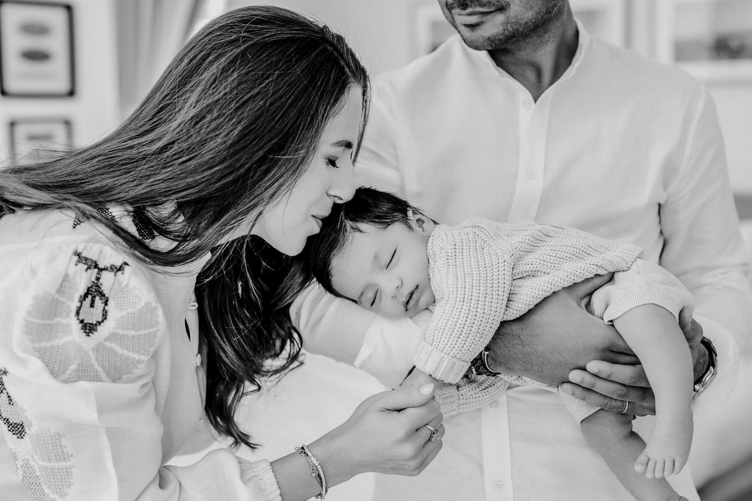 Family lifestyle portrait showing tender moments between parents and child in white room.
