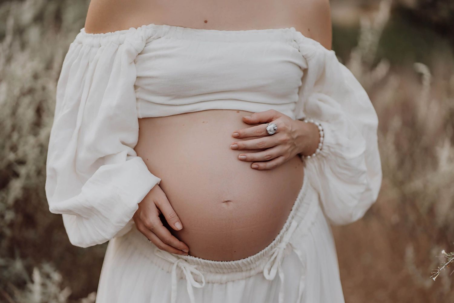 Side view maternity shots showing pregnancy silhouette in white dress.