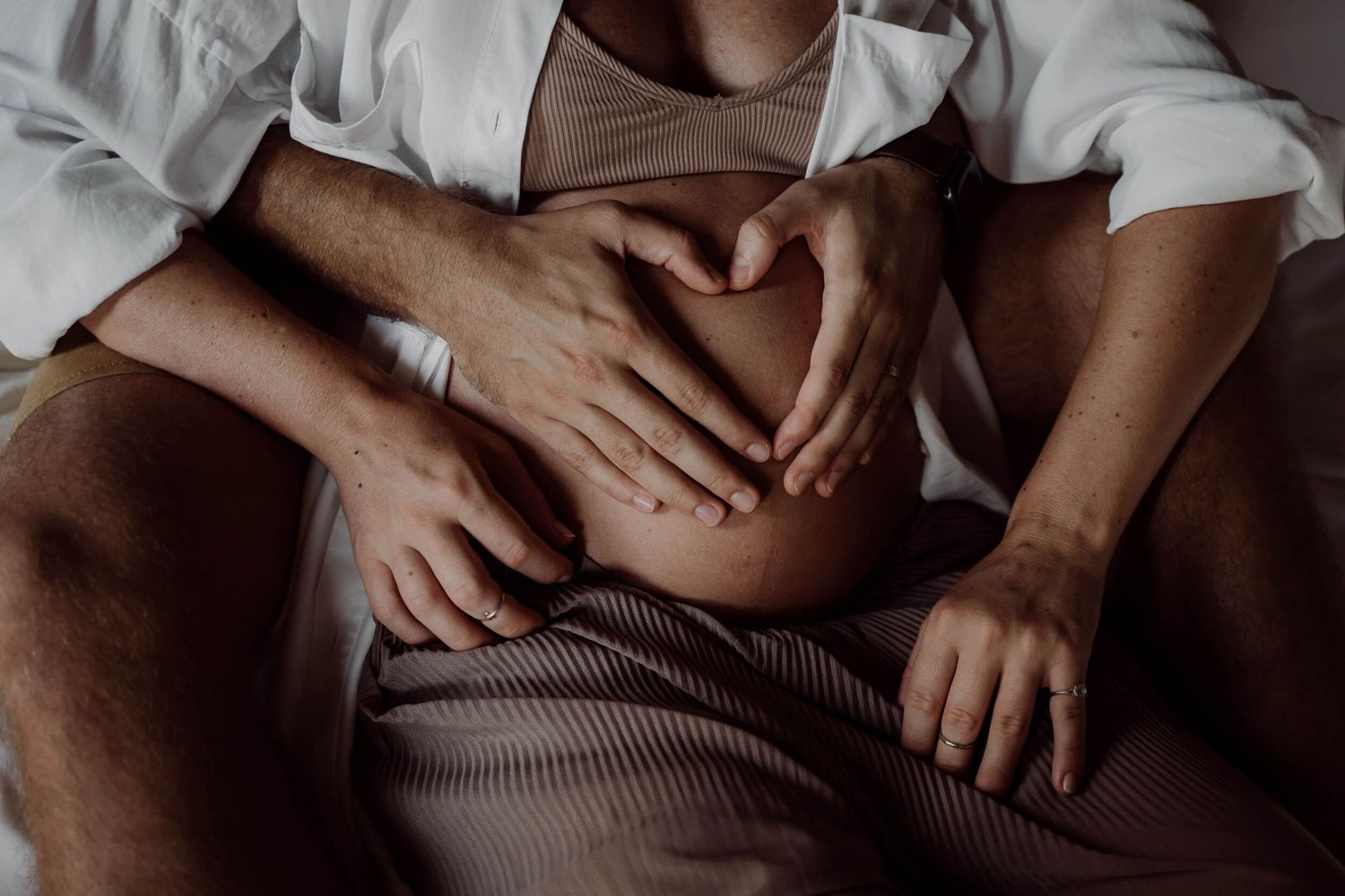 Close-up images of hands gently touching and creating intimate gestures against a dark background.