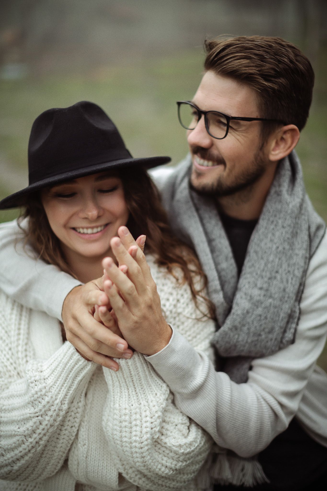 A couple in cozy sweaters share intimate moments and laughter while cuddling together outdoors.