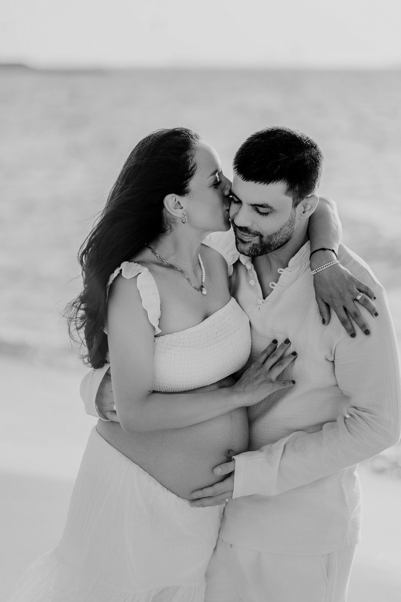 Romantic black and white photo series showing tender intimate moments between a couple at the beach.