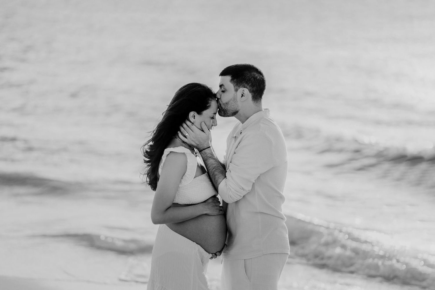 Series of black and white romantic beach photographs showing couple embracing by the ocean during sunset.