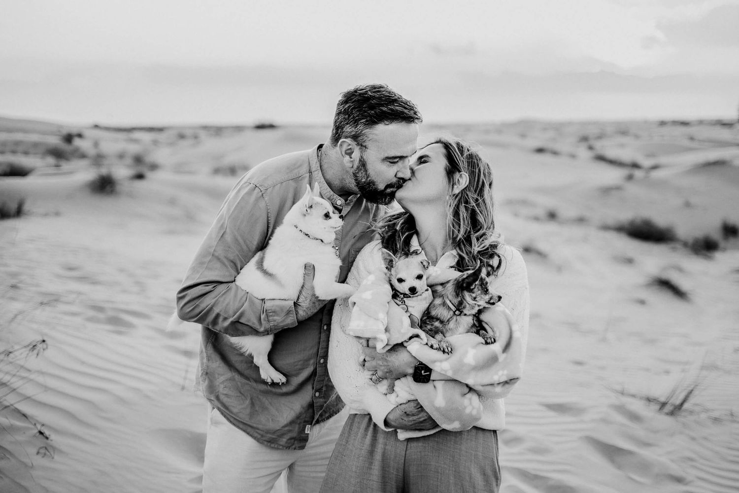 Family portrait with a chihuahua puppy among sand dunes at golden hour.