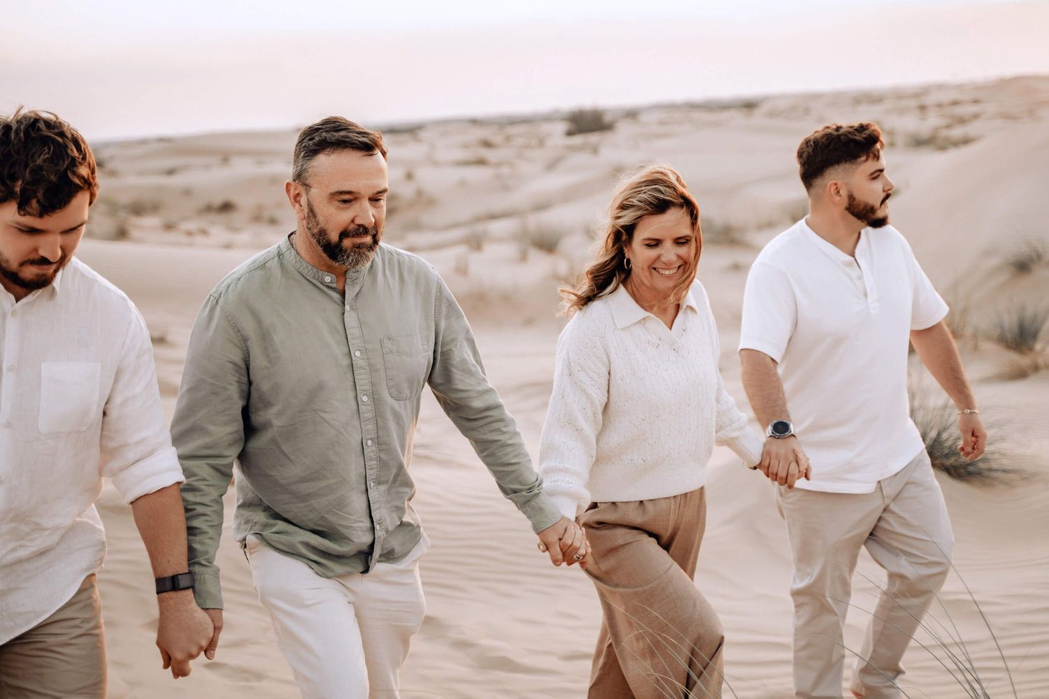 Friends walking together across desert landscape wearing coordinated neutral tones.