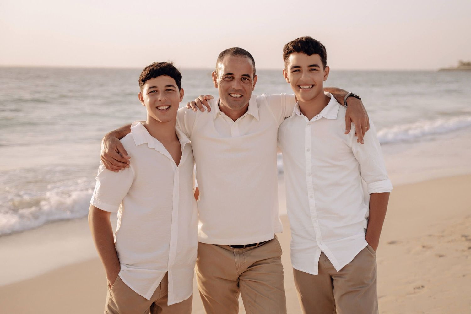 Sunset beach photography session with group wearing matching white and khaki outfits.