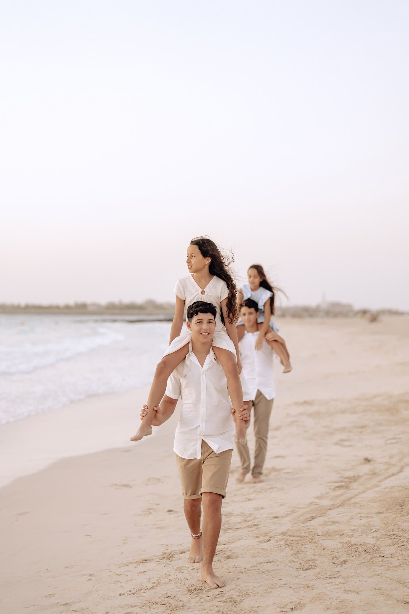 Young people playing and having fun while walking along a scenic beach at sunset.