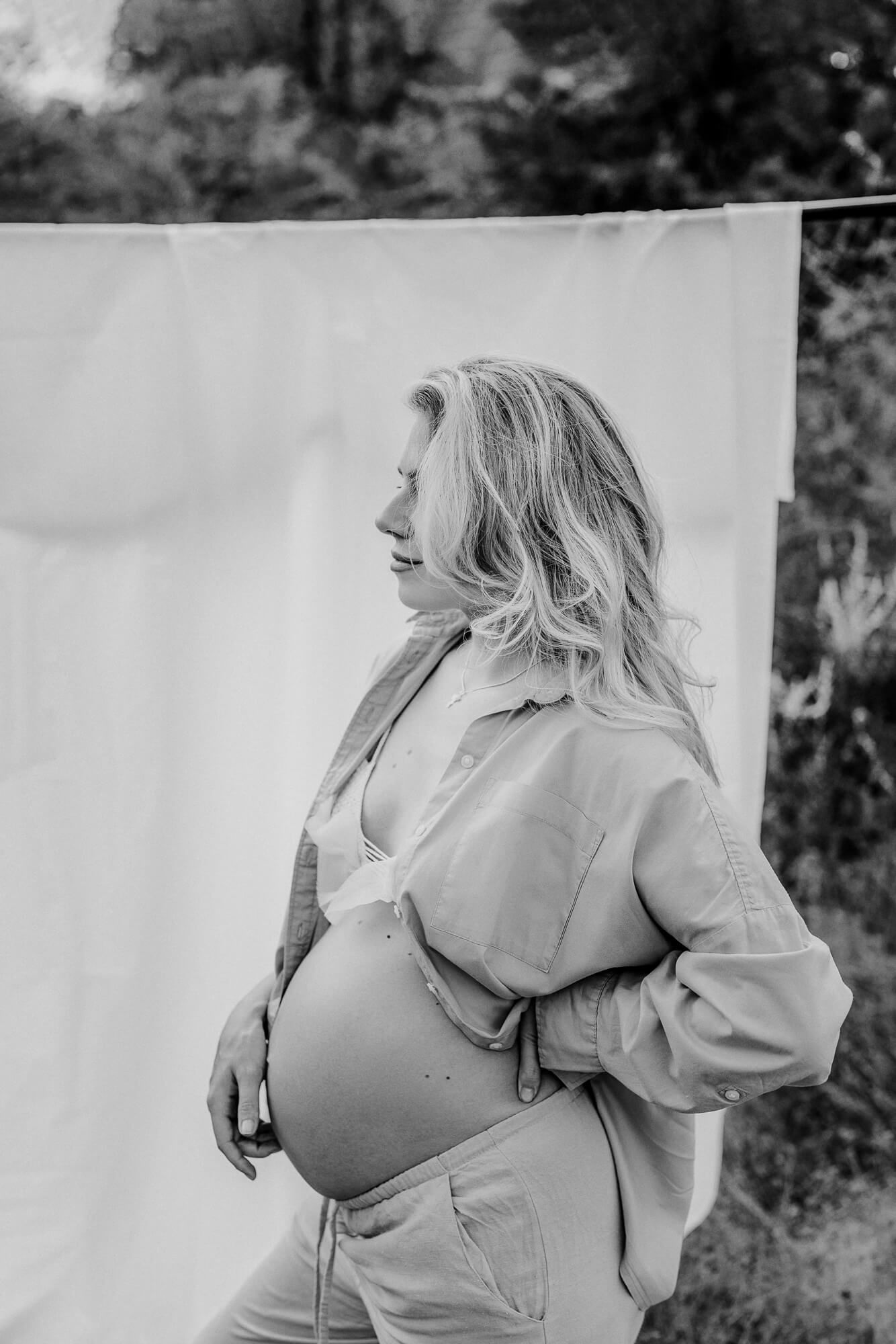Black and white maternity portrait with soft natural lighting and denim shirt details.