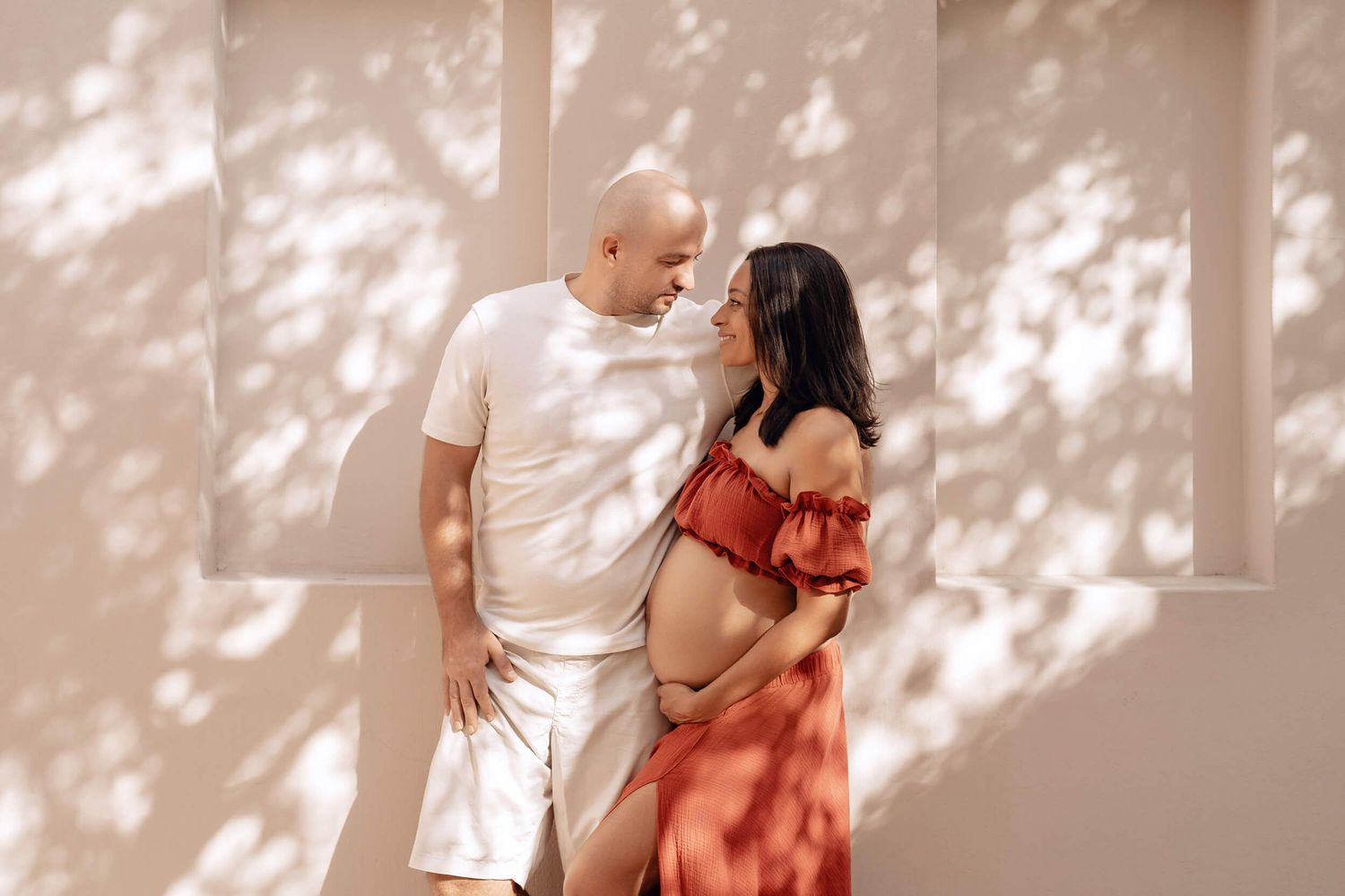 Romantic maternity session with dappled sunlight creating artistic shadows.