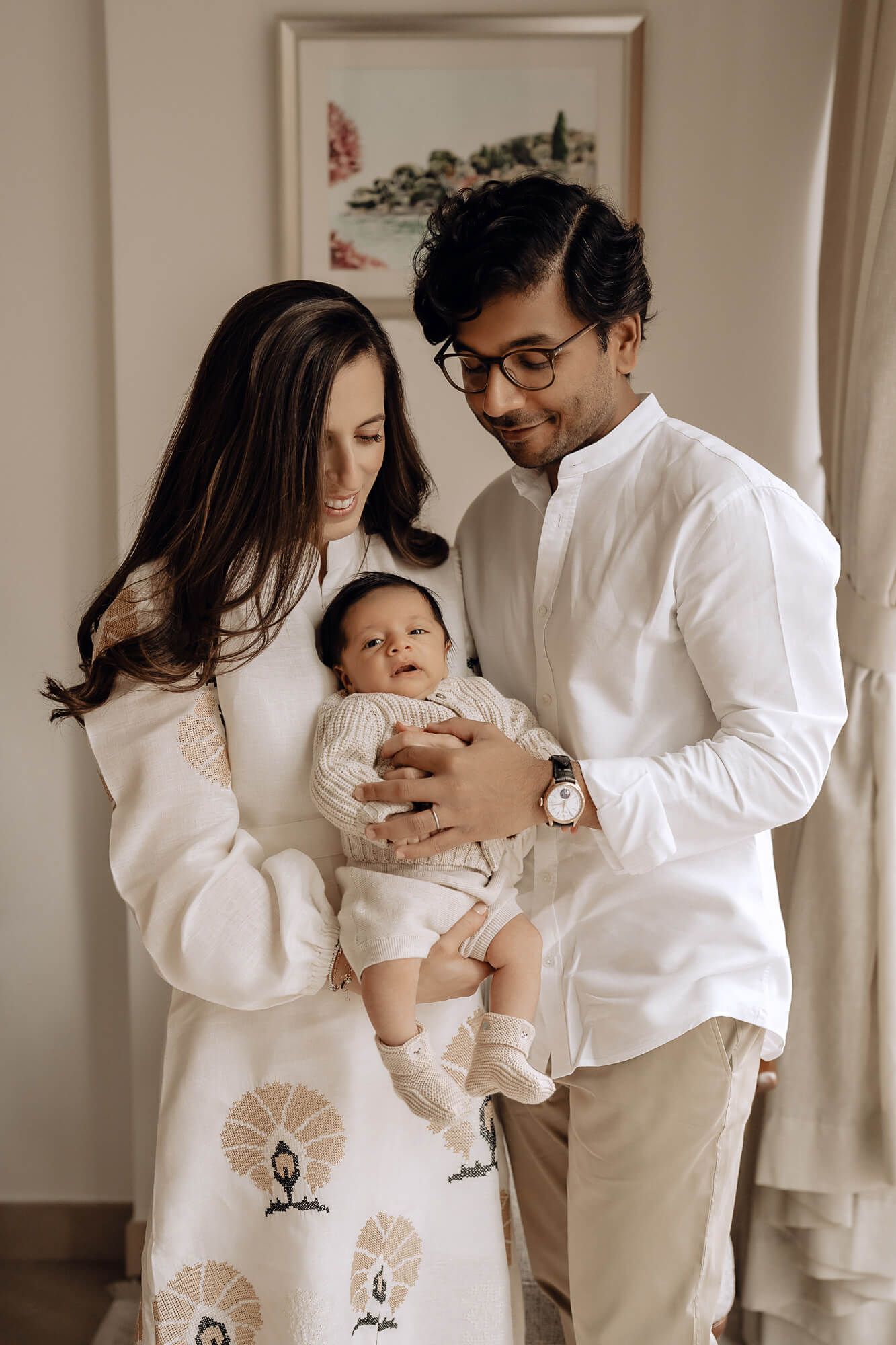 Family photo series in white outfits showing playful moments with their baby.