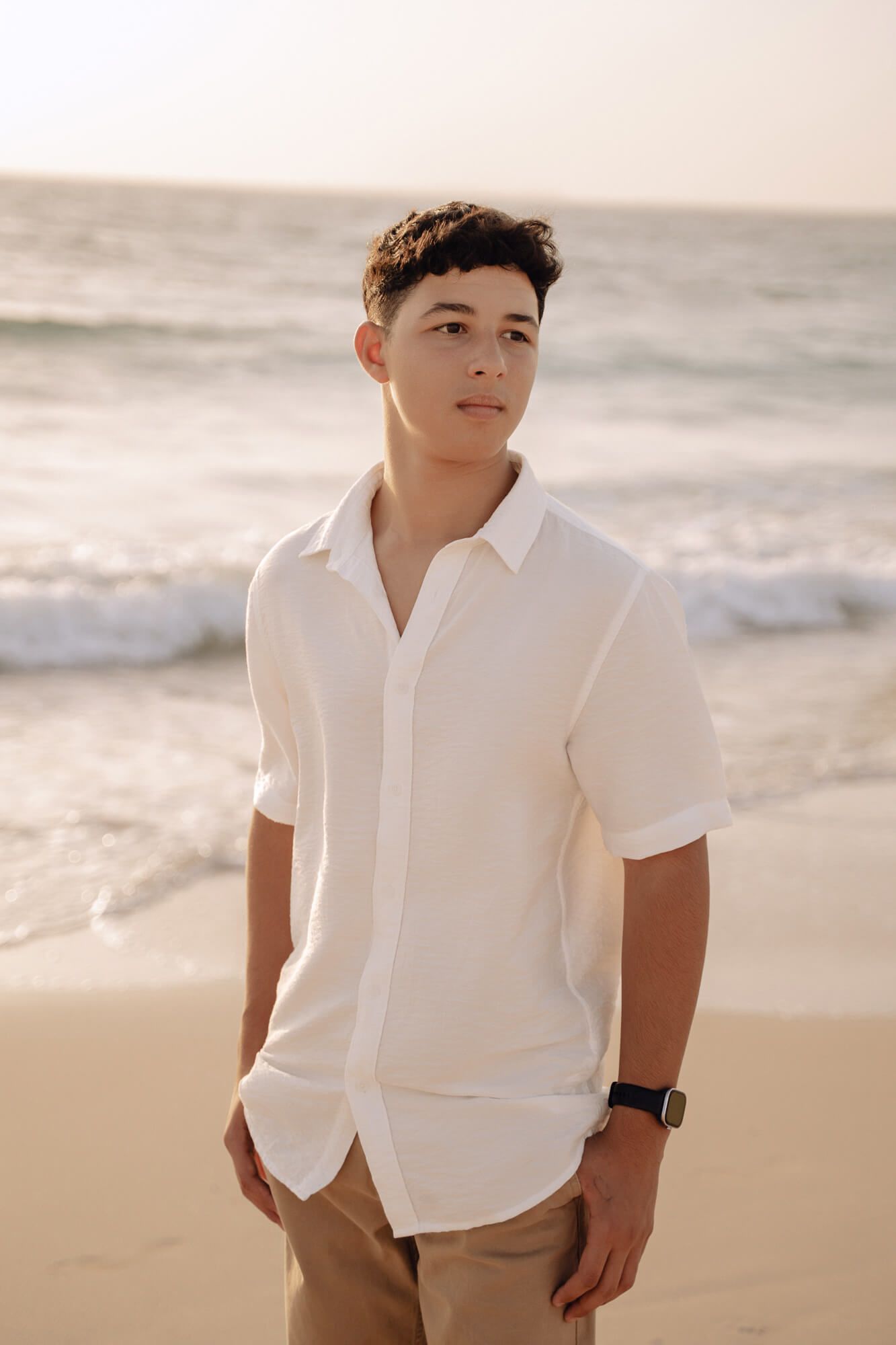Portrait of person in white button down shirt posing against ocean backdrop.