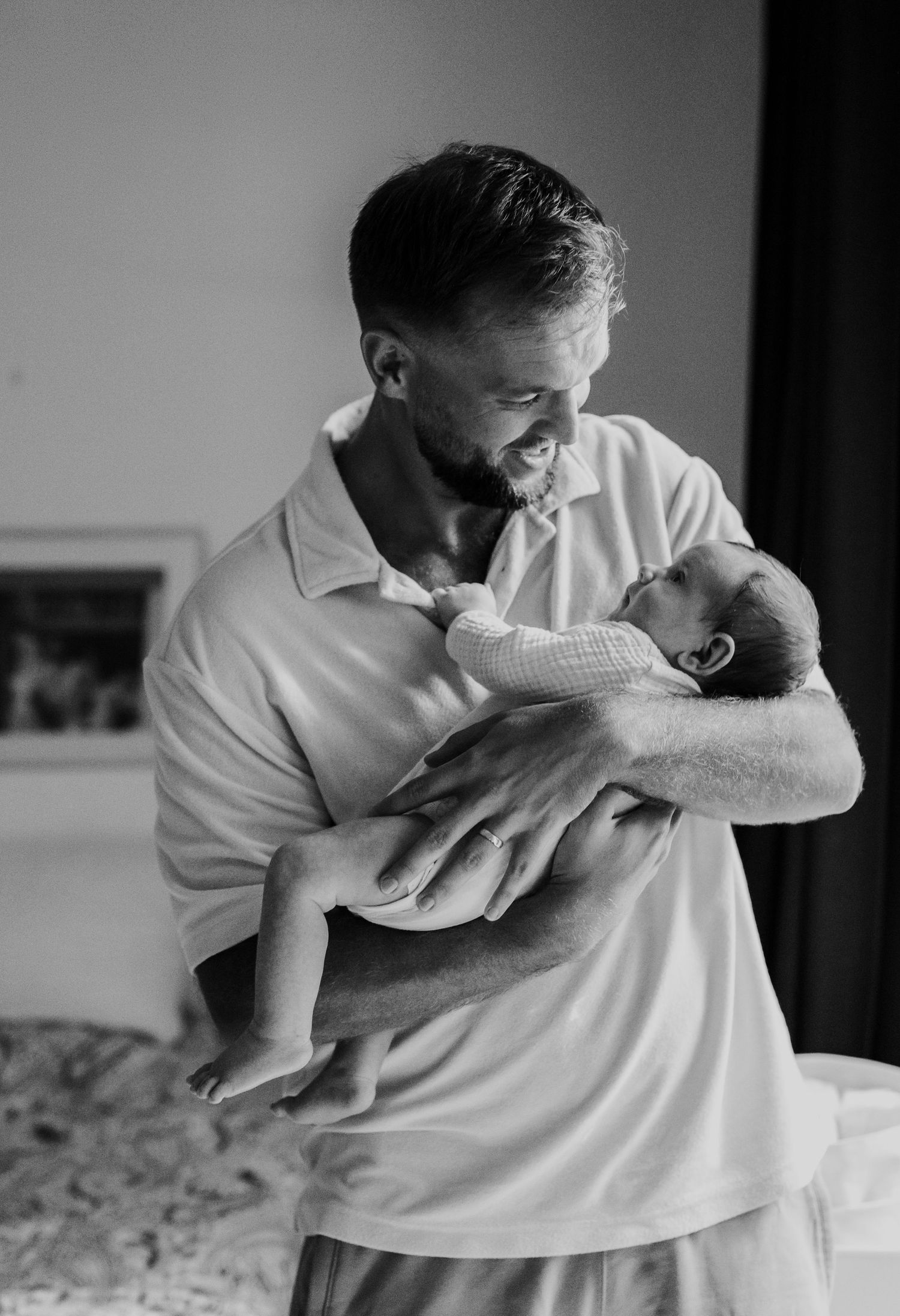 A tender black and white moment of a parent cradling and gazing lovingly at their newborn baby.