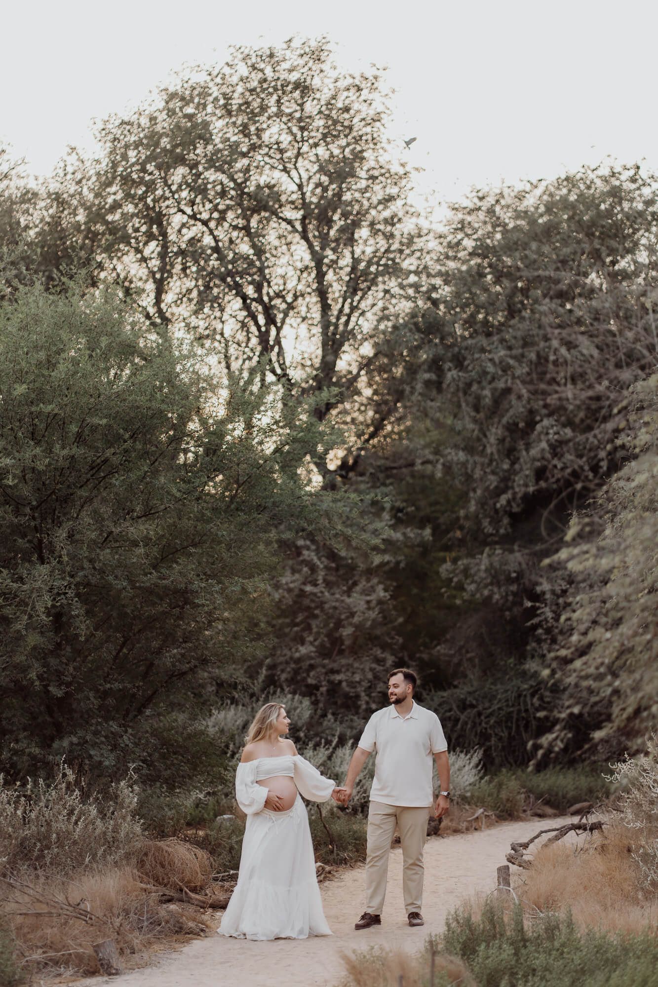 Desert maternity photography session captured during sunset among native brush and trees.