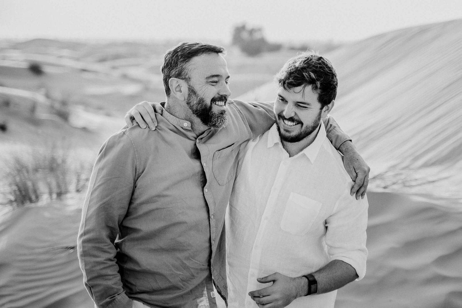 Natural light portrait of two people sharing genuine laughter in desert setting.