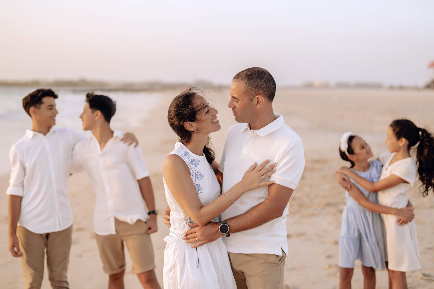 Three couples posing intimately on beach during sunset photography session.