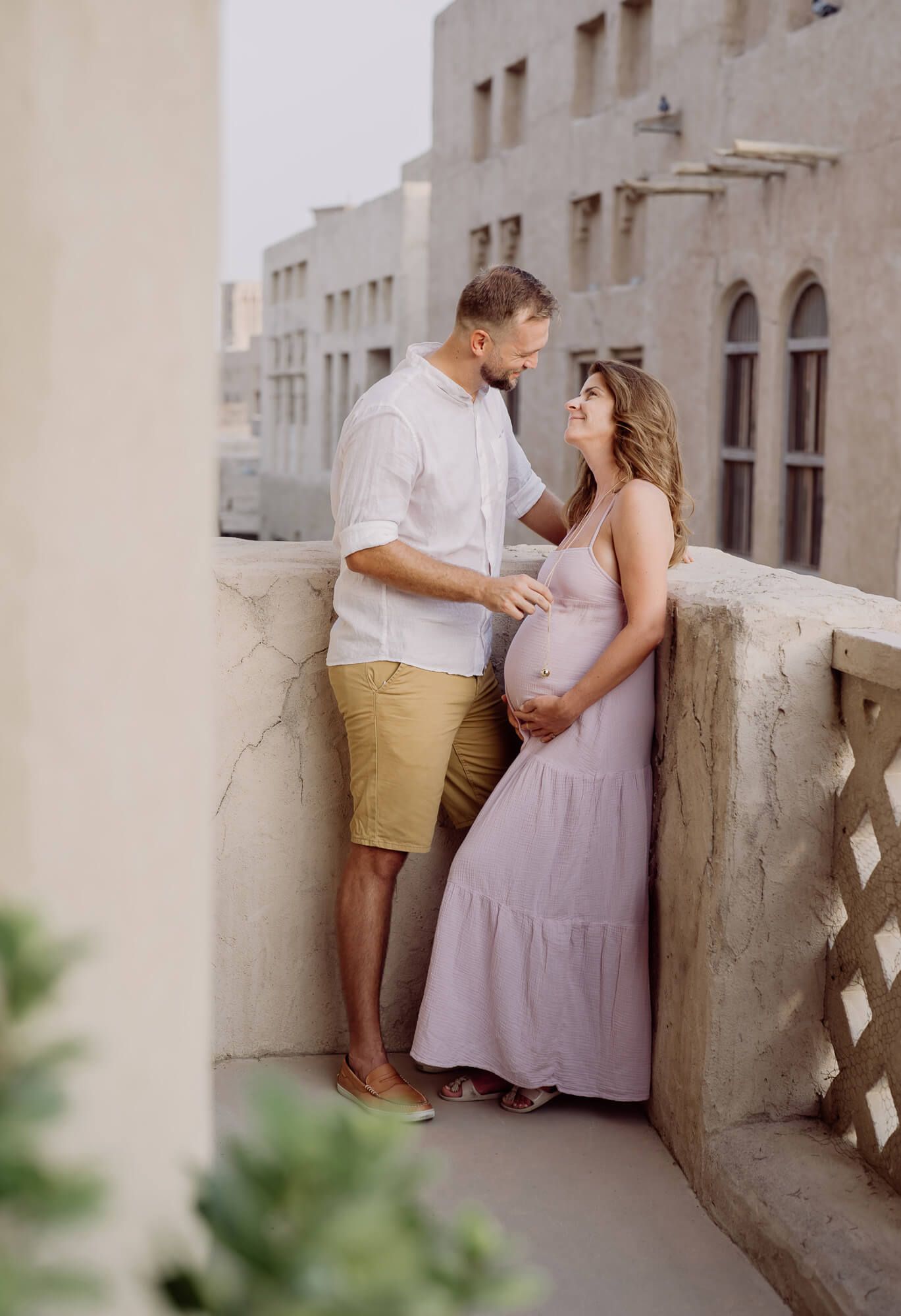Romantic couple embracing in vintage architectural setting wearing soft pastel outfits.