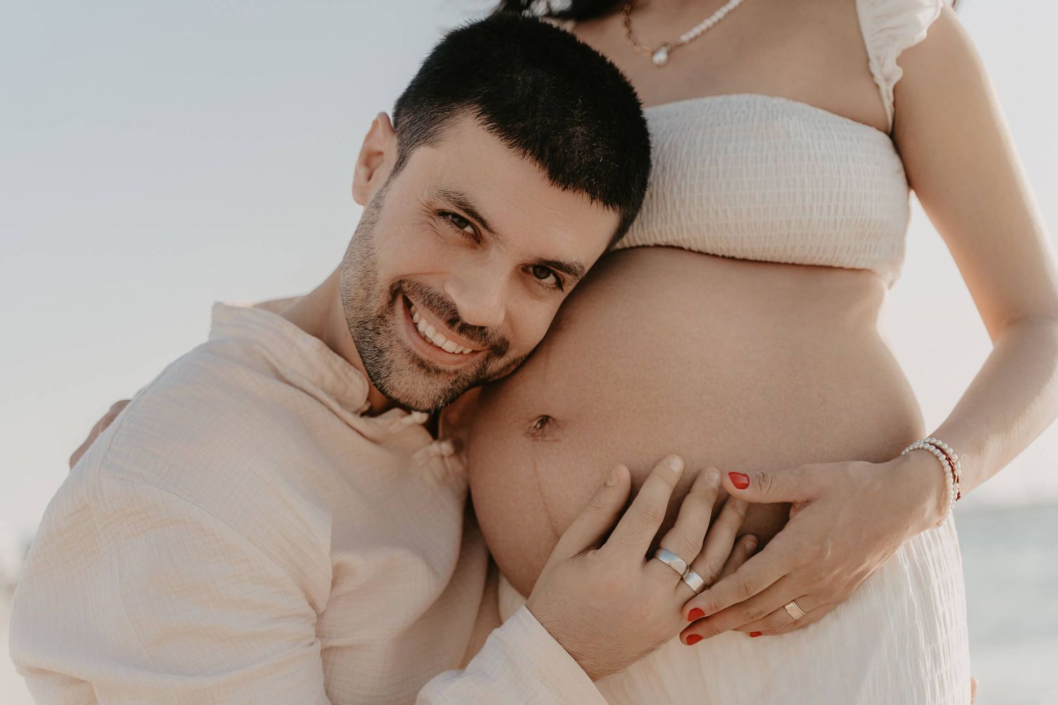Close-up photo showing expectant parents together, with gentle hands lovingly touching a pregnant belly.
