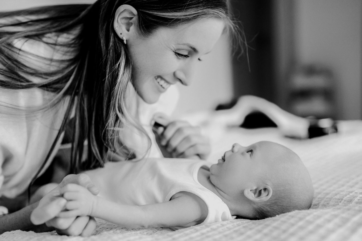Mother lying in bed sharing tender skin-to-skin bonding moments with newborn baby.