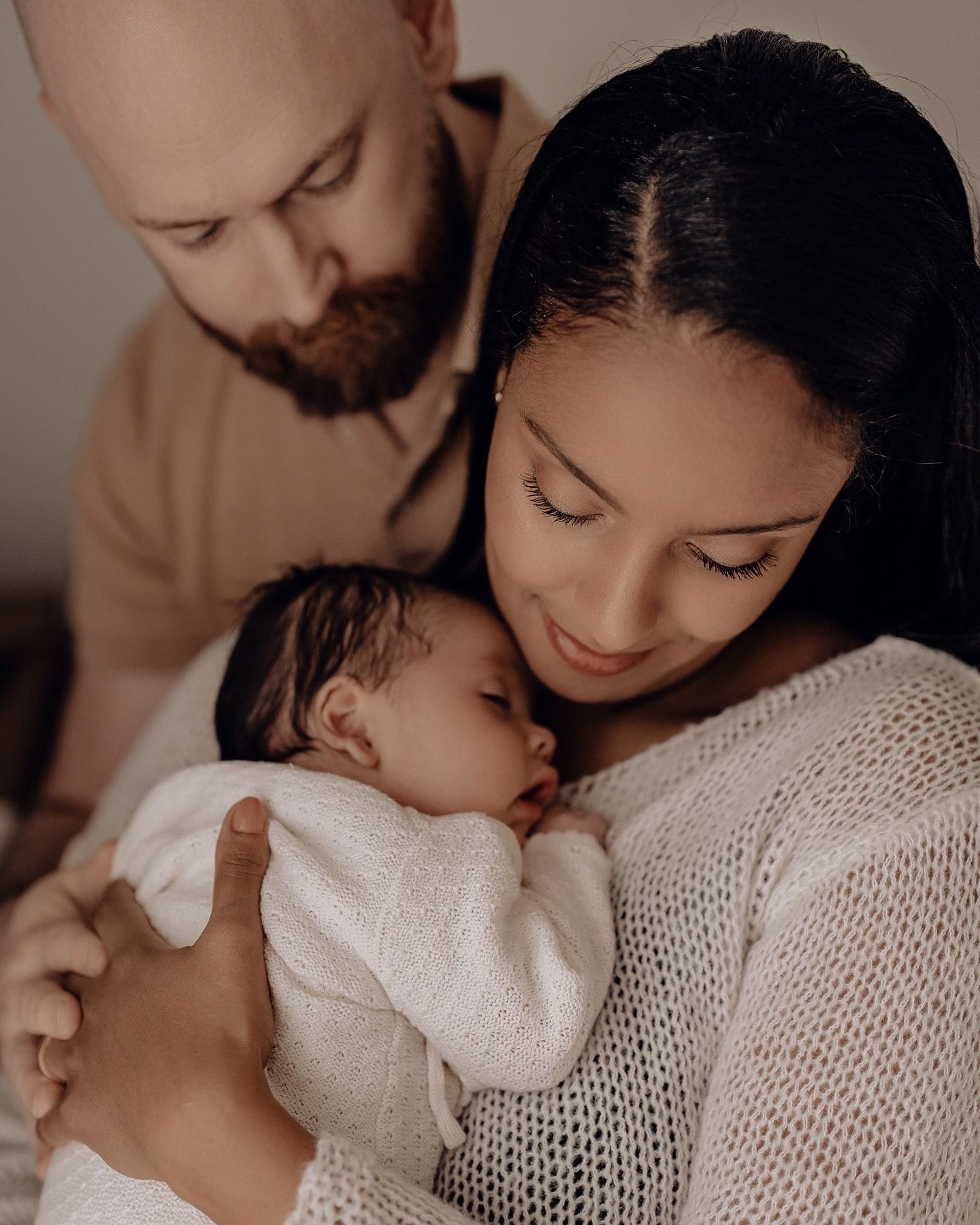 Intimate family portrait showing tender moment with newborn baby in soft lighting.