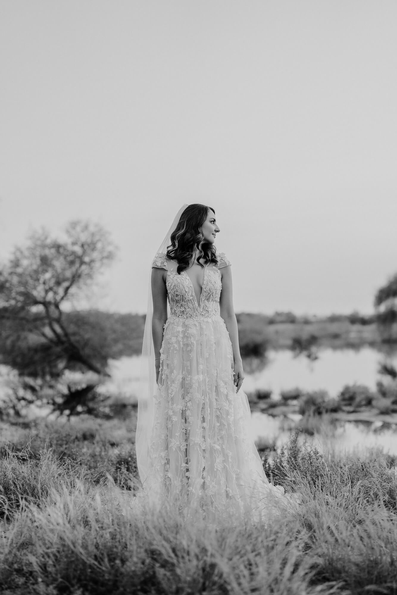 Black and white panoramic series showing a figure in a lacy white dress standing in a desert landscape with shrubs and trees.