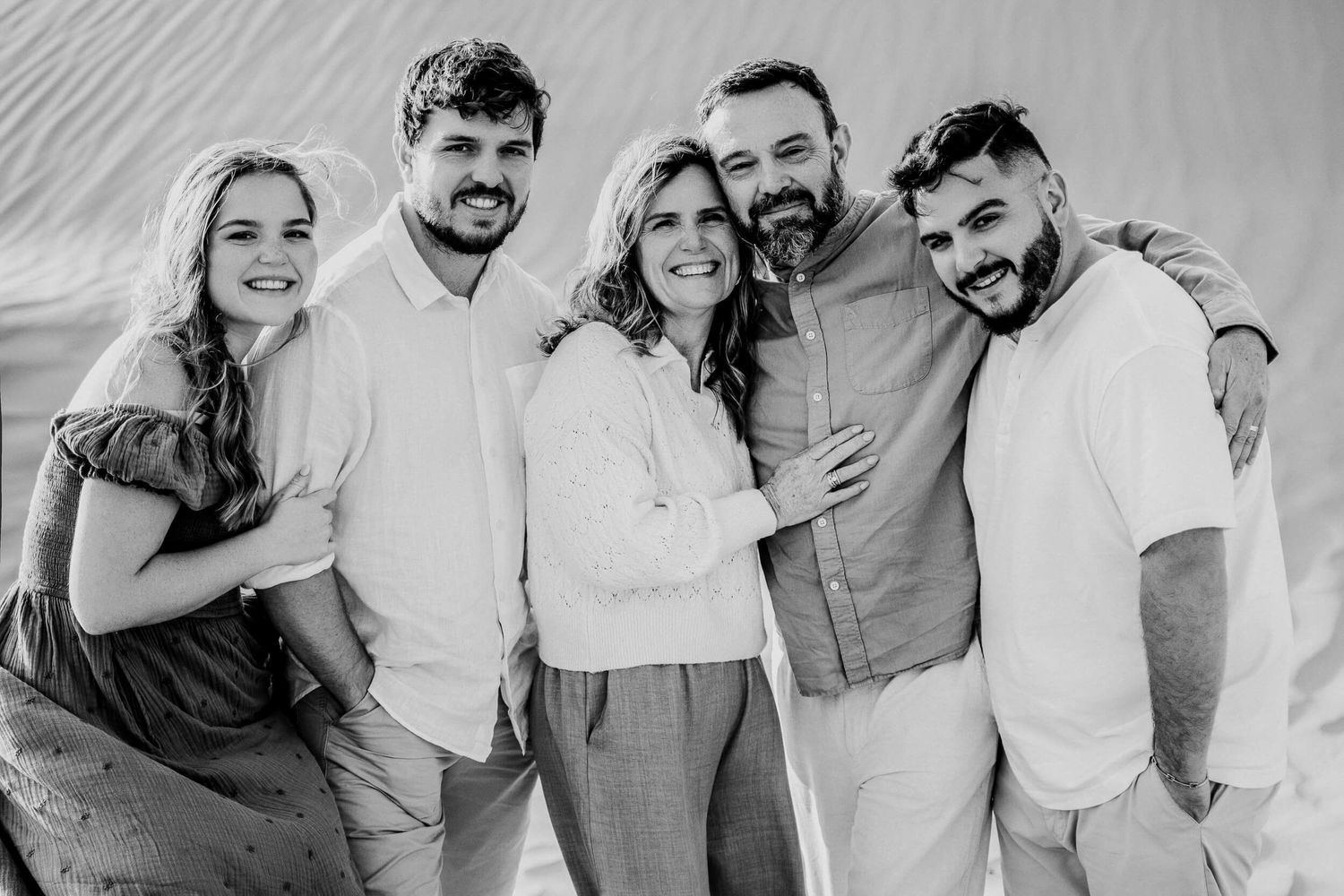 Black and white group portrait of five people in light clothing against desert background.