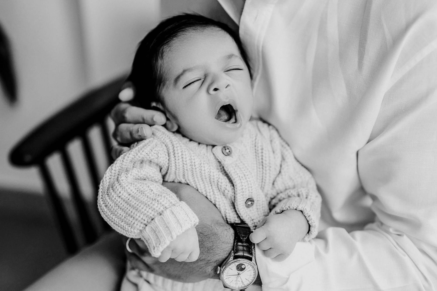 Black and white portrait of baby yawning while wearing knit sweater.
