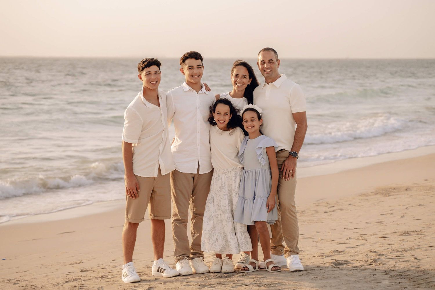 A beach family photo session at sunset with casual white and khaki outfits.