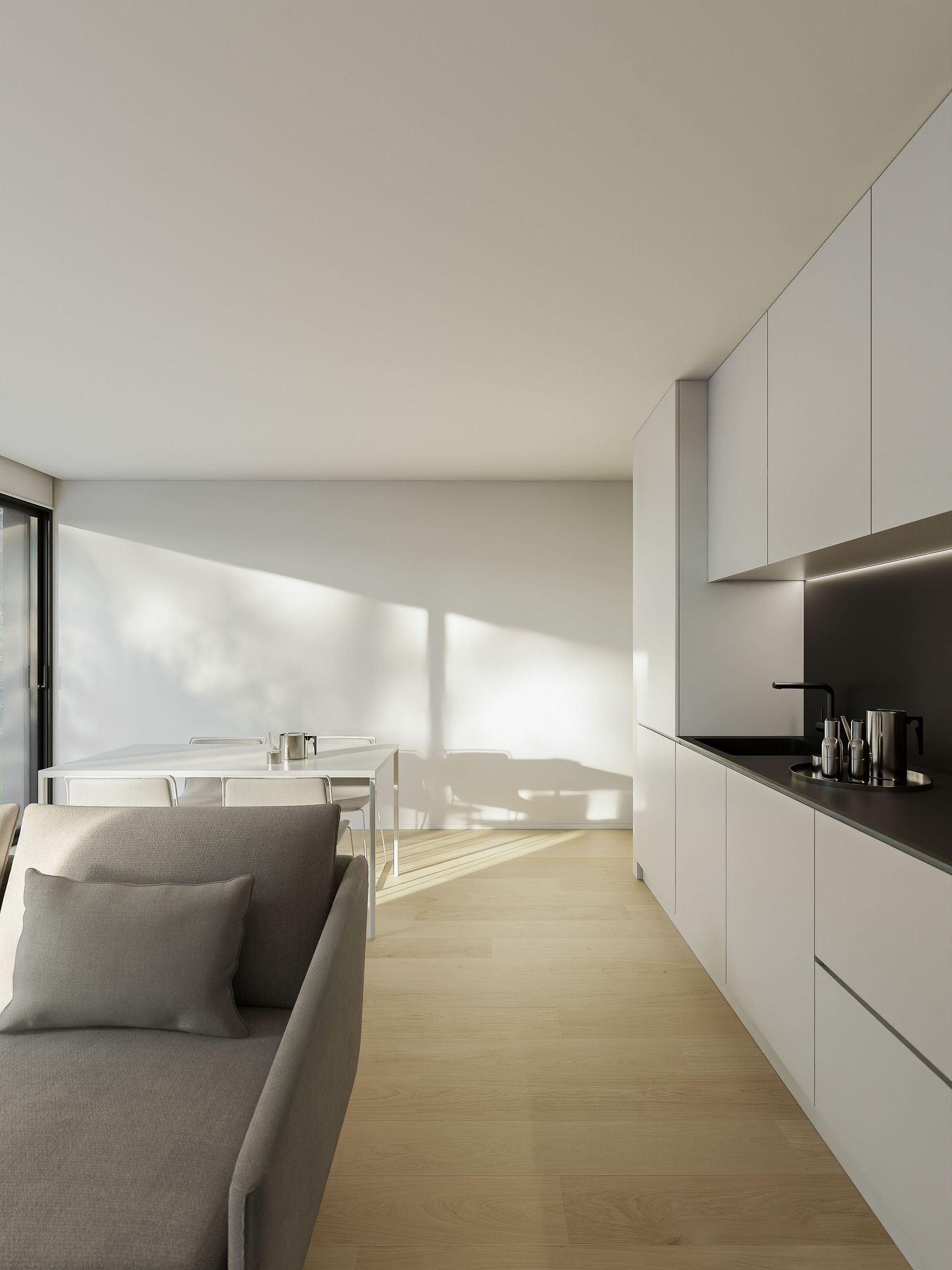 Minimalist white interior with long corridor featuring gray seating and natural light streaming through windows.