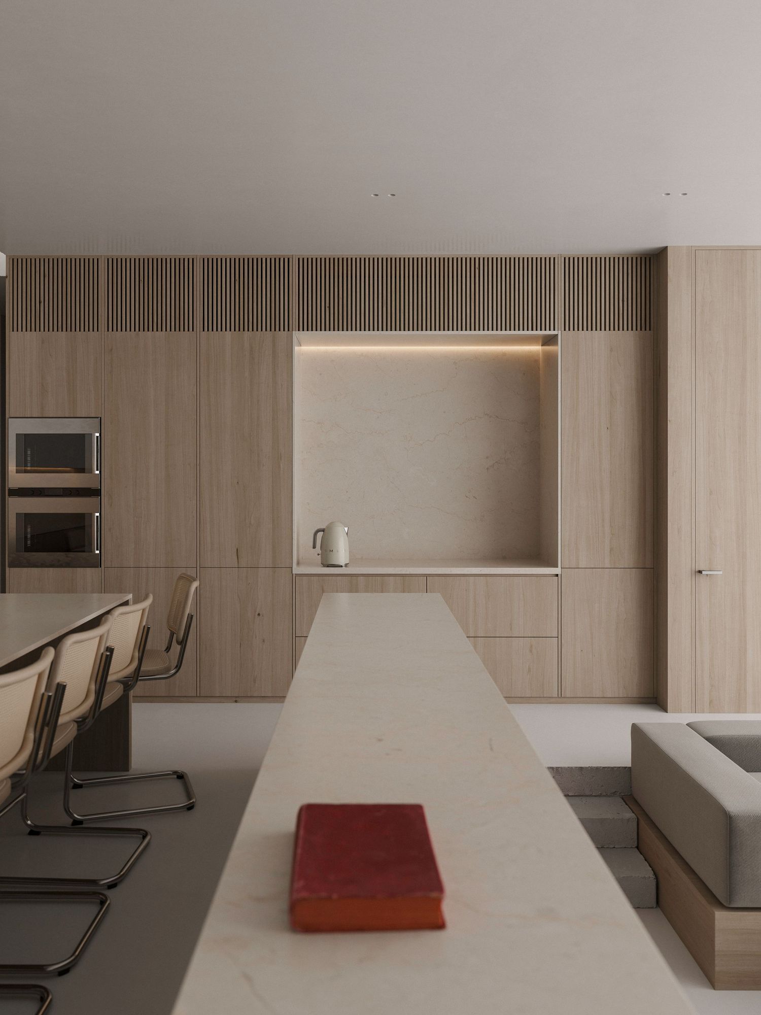 Minimalist modern kitchen featuring a long white counter, cantilever chairs, and light wood cabinetry with built-in appliances.