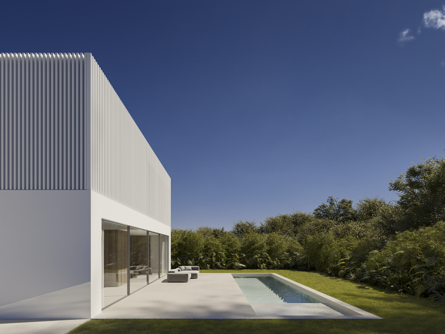 Modern white minimalist house with swimming pool and patio surrounded by lush green landscape under blue sky.