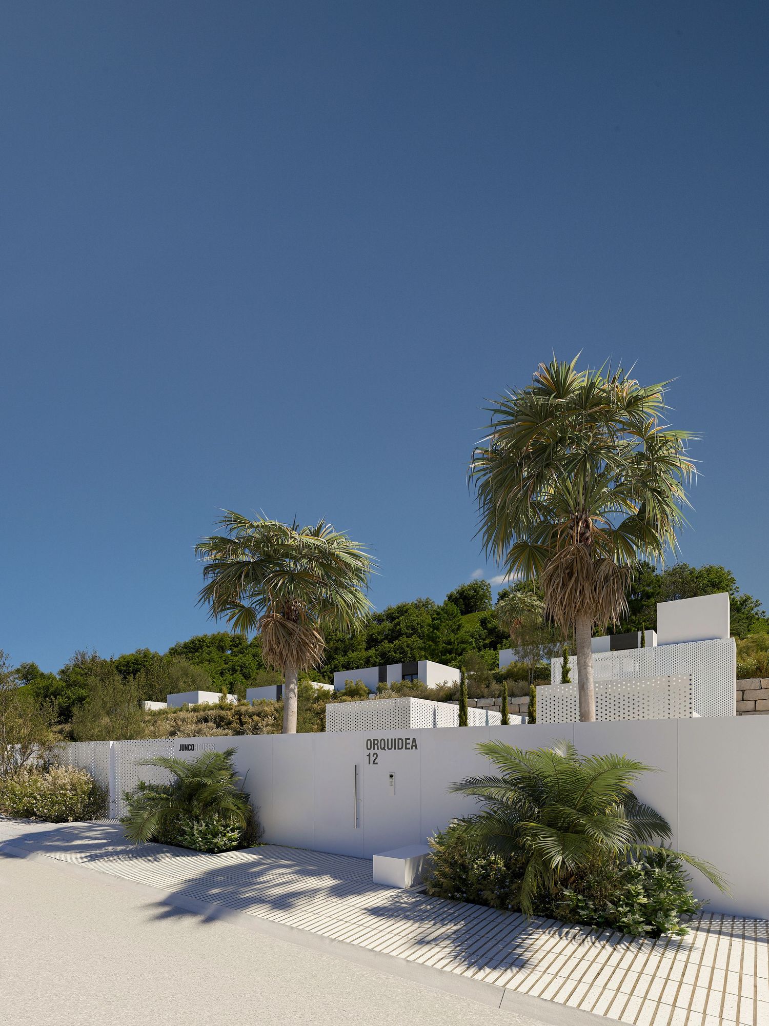 White modern beach house with palm trees against bright blue sky and white sand landscape.