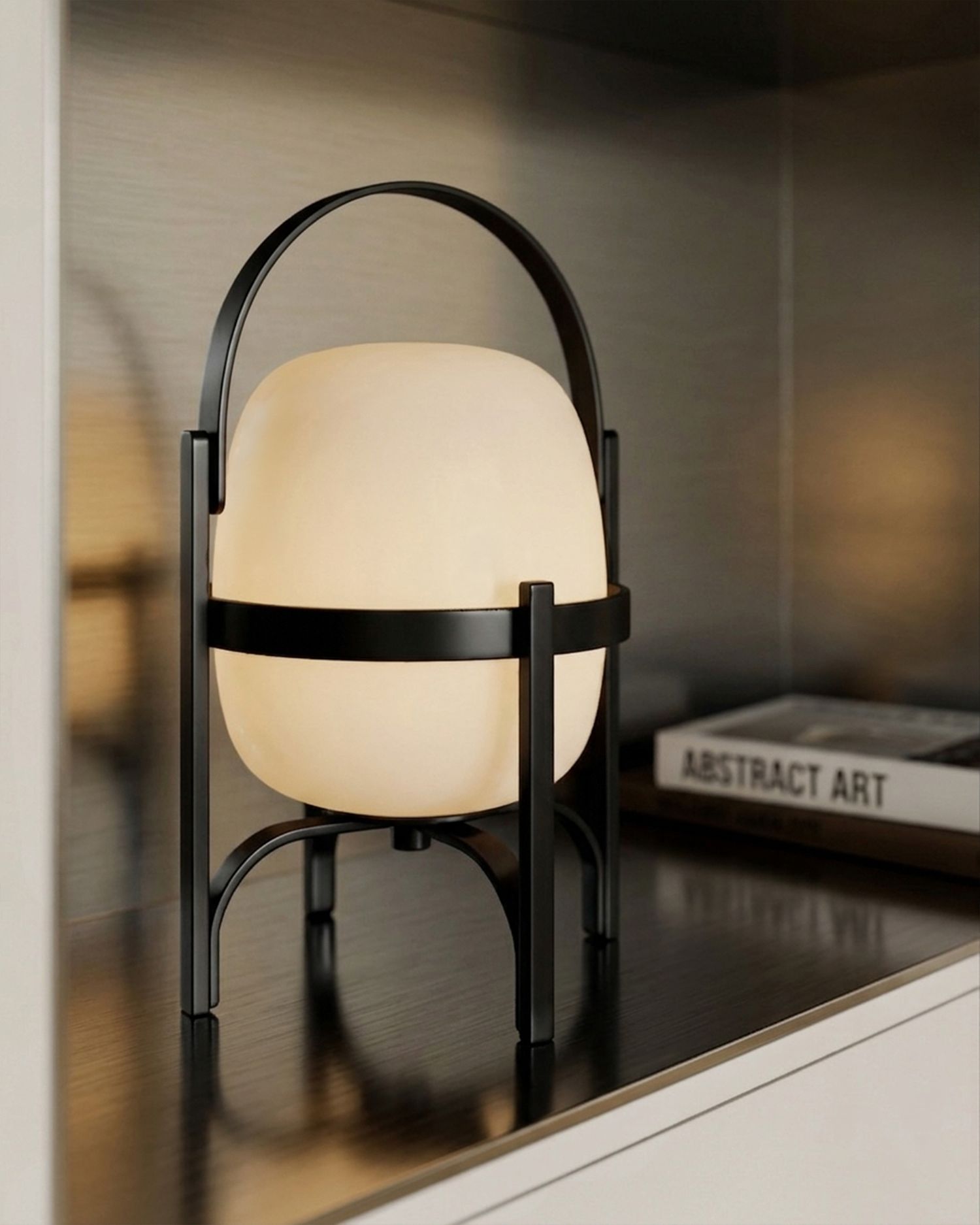 Black metal arc lamp with frosted globe shade on a shelf beside an Abstract Art book.