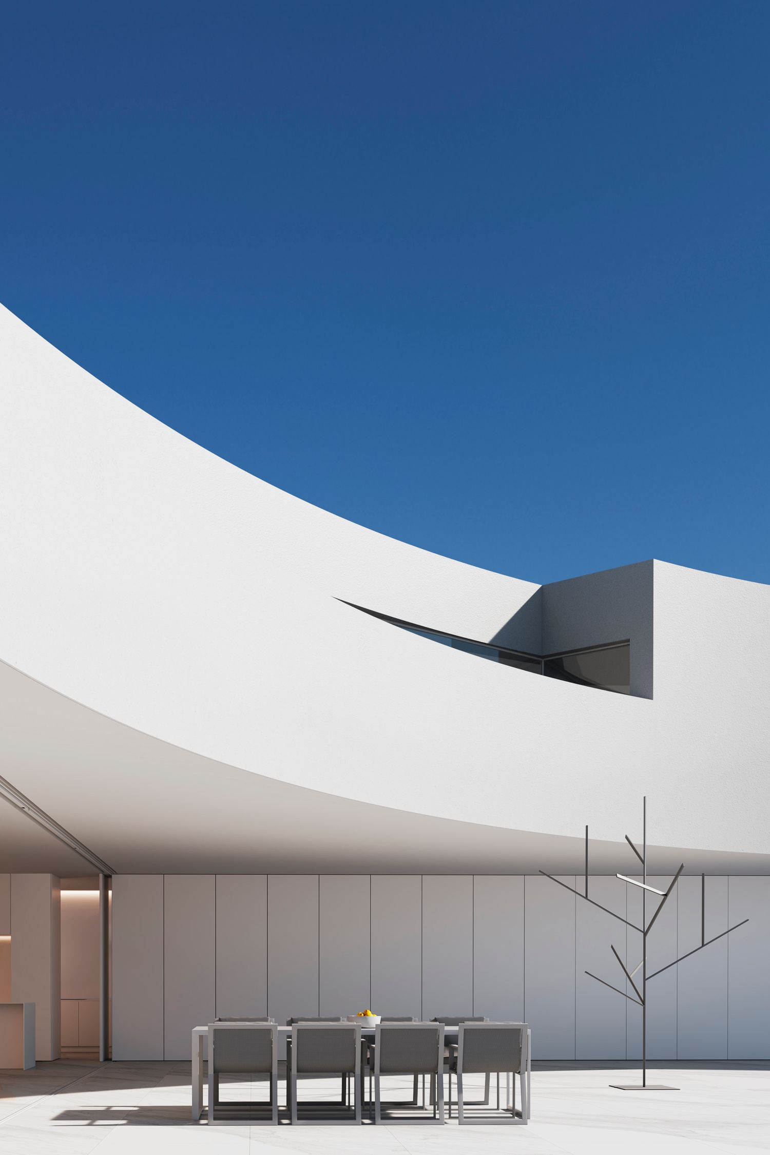 Minimalist outdoor dining area with white furniture under curved architectural elements and blue sky.