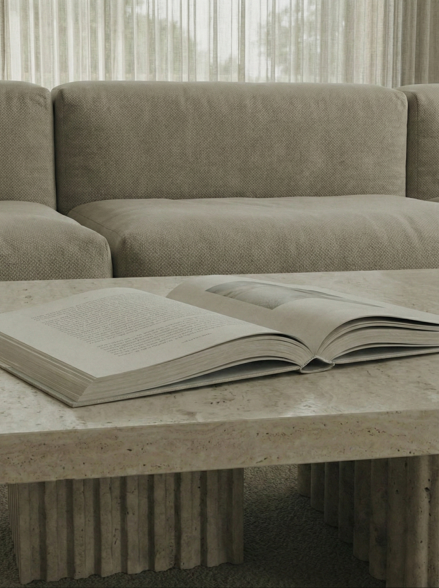 An open book with white pages lies on a gray concrete surface, photographed in black and white tones.