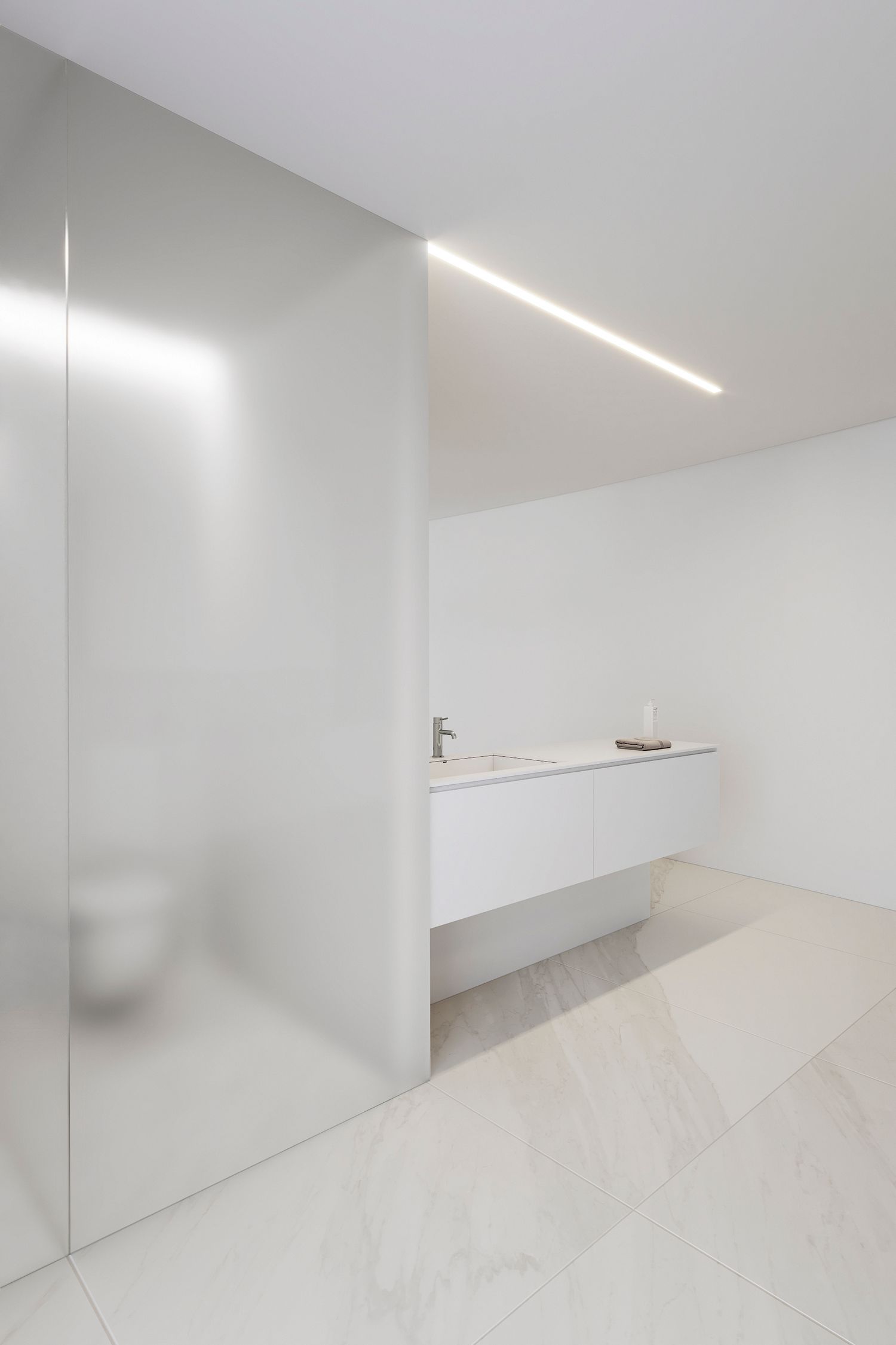 Minimalist white interior space with sleek recessed lighting and floating shelf design.