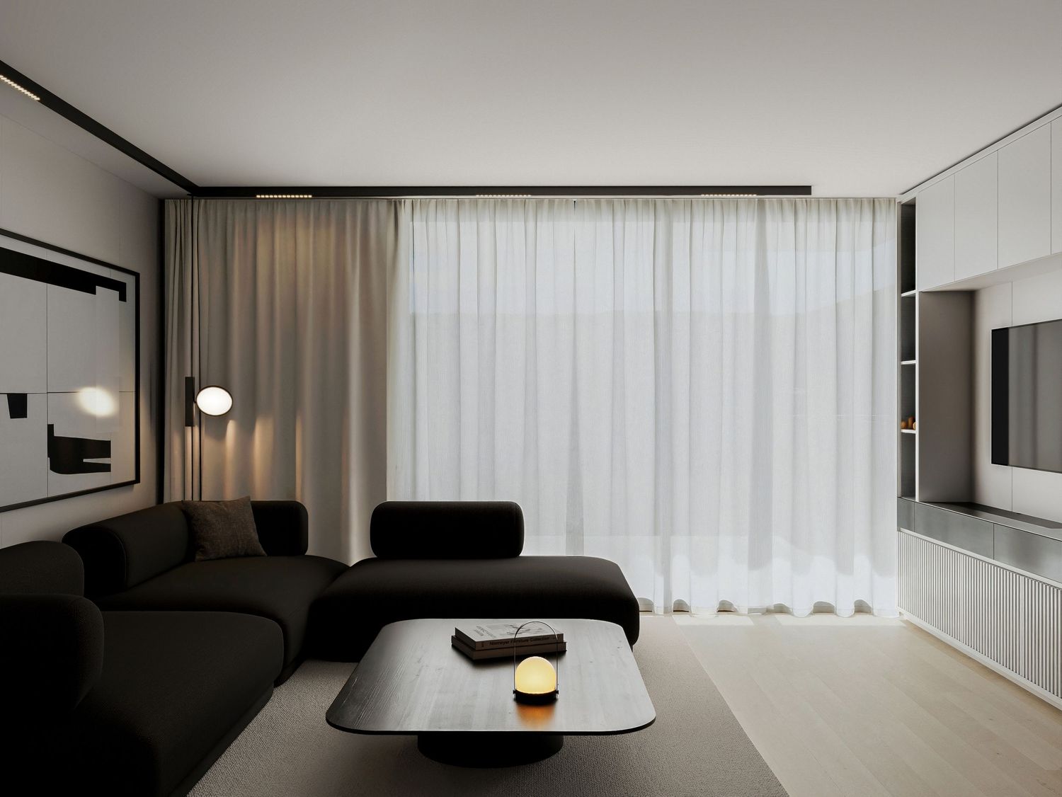 Modern minimalist living room with black sectional sofa, sheer white curtains, and sleek white built-in cabinets on light wood floors.