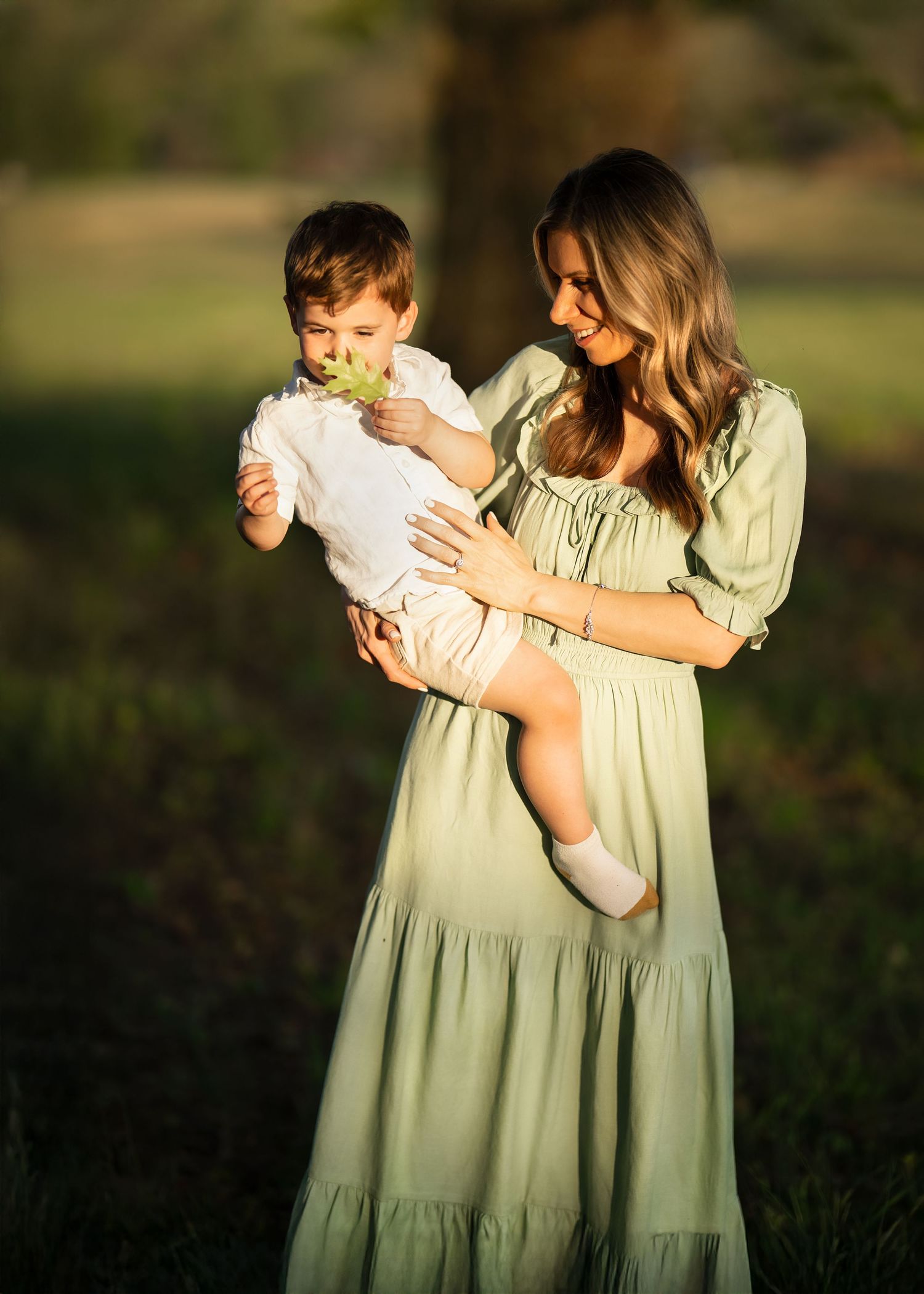 A mother holding her toddler son outdoors in golden hour light during her Mommy & Me portrait session on the Main Line, PA.