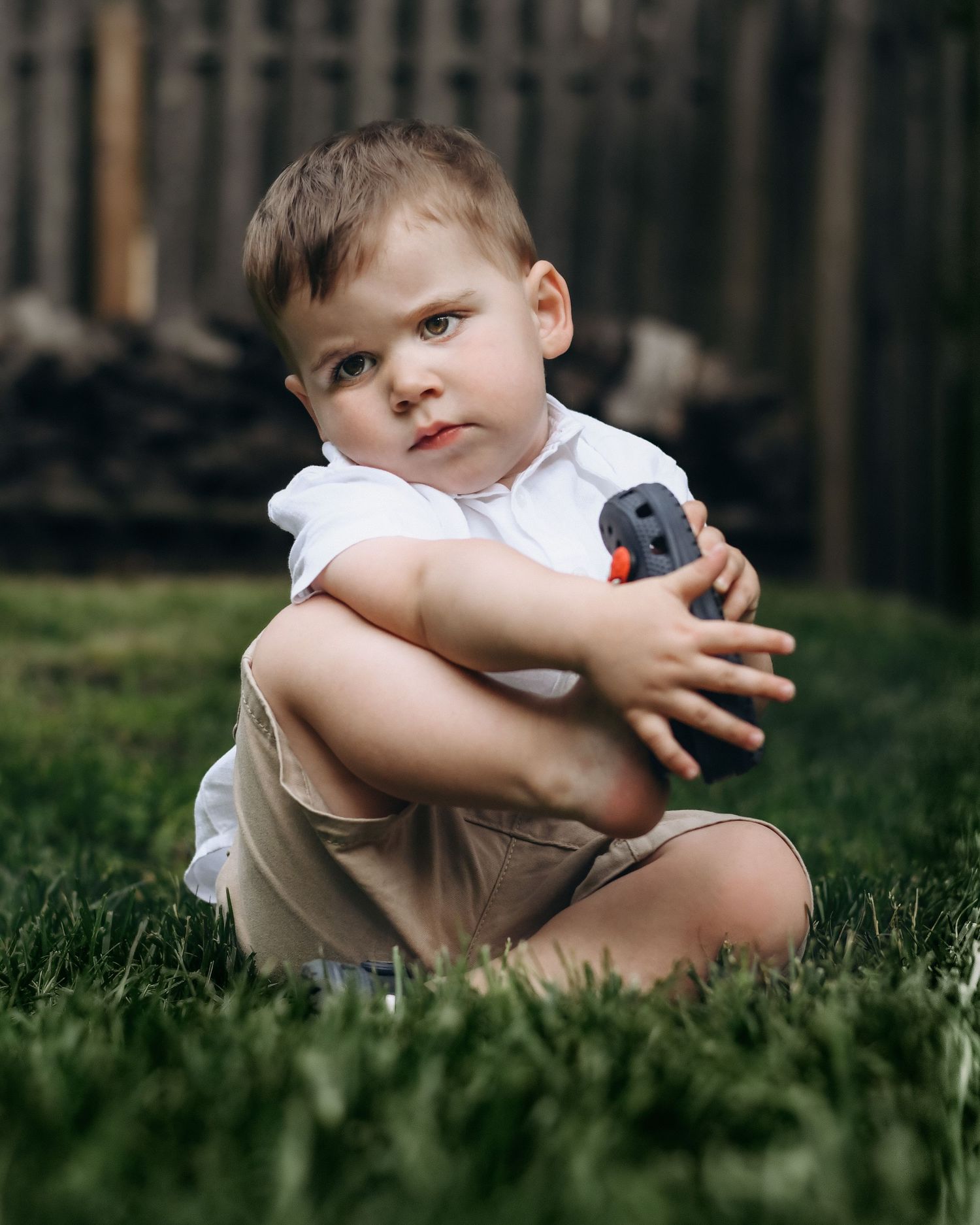 Child sitting in green grass during an outdoor photo session.