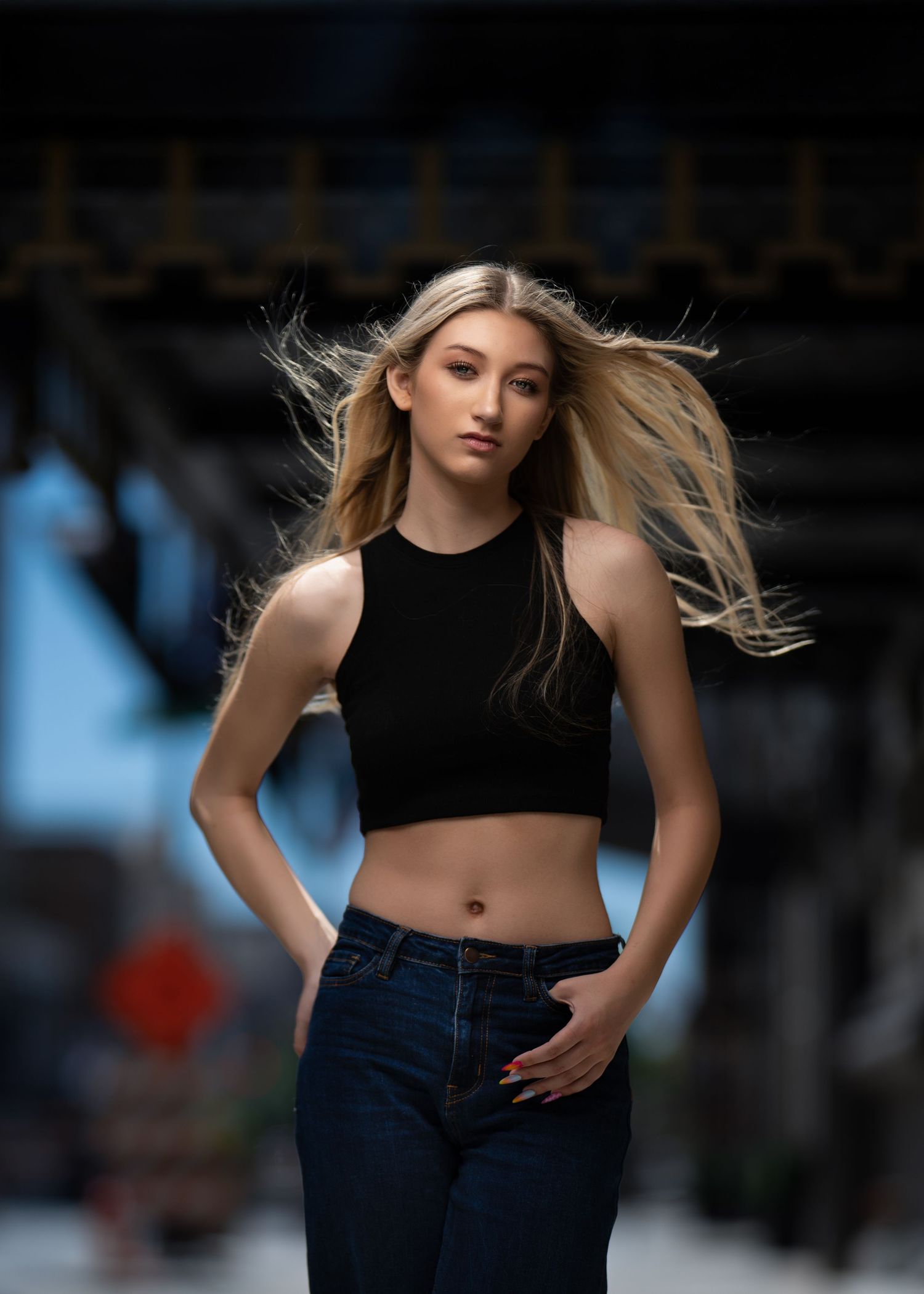 A high school senior posing outdoors with hair blowing in the wind during her glam portrait photo session near Wayne, PA.