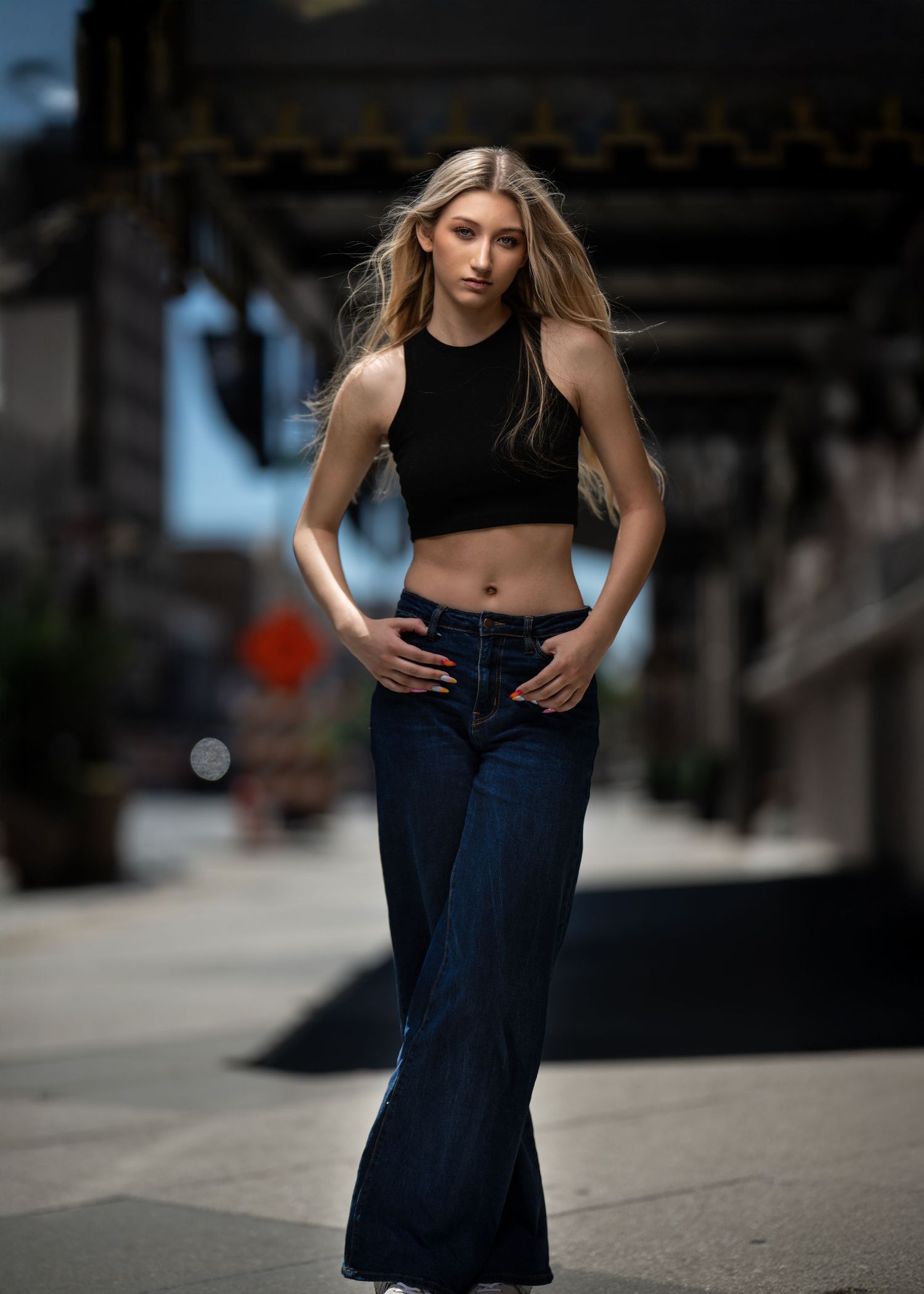 A high school senior posing outdoors with hair blowing in the wind during her glam portrait photo session on the Main Line, PA.